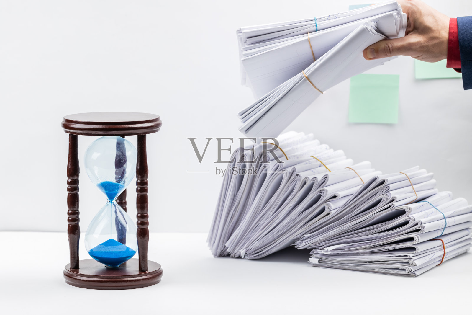 文书工作期限的概念。一个最小工作空间的侧视图，前面有一大堆文件和沙漏。工作组织的概念。影棚拍摄。本空间照片摄影图片