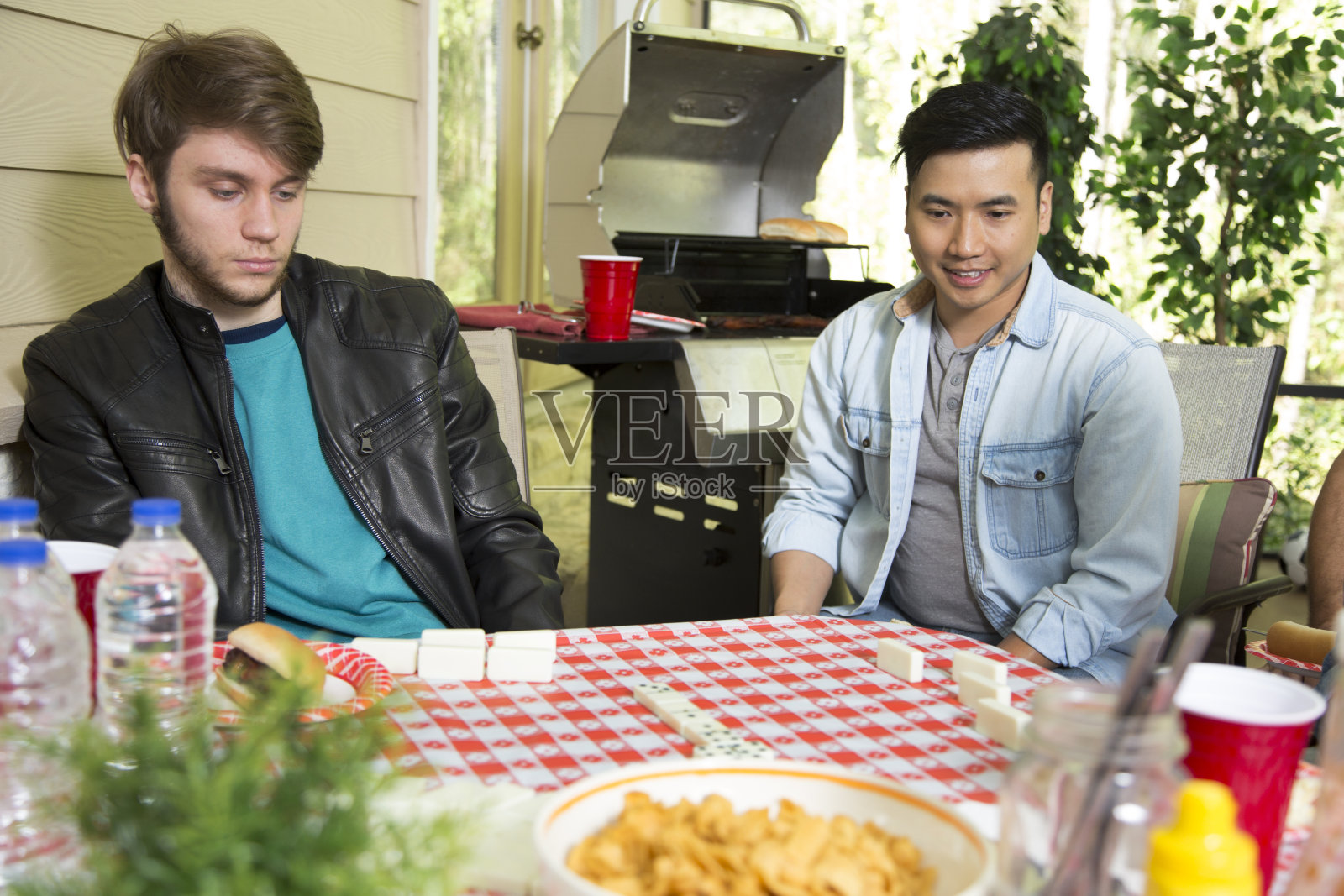 多民族的年轻男子在外面做饭。照片摄影图片