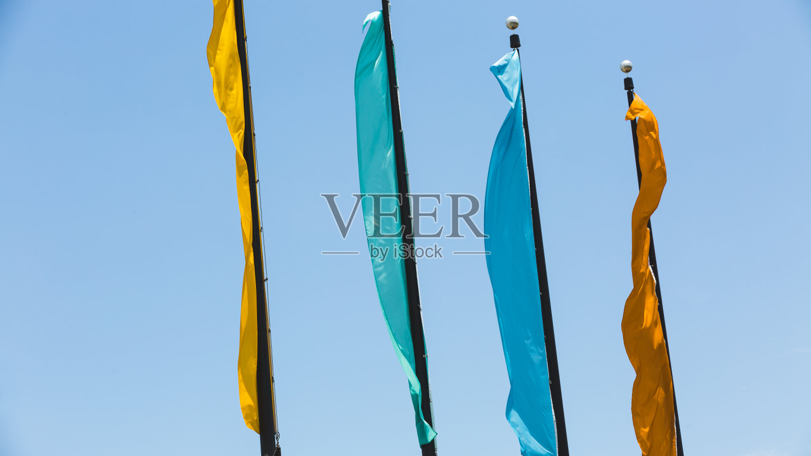 四面旗子随风摇曳，天空湛蓝照片摄影图片