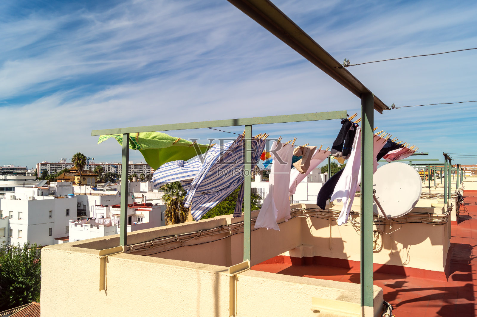 秋日阳光明媚的塞维利亚(塞维利亚，安达卢西亚)，一幢建筑的屋顶上挂着衣服。照片摄影图片