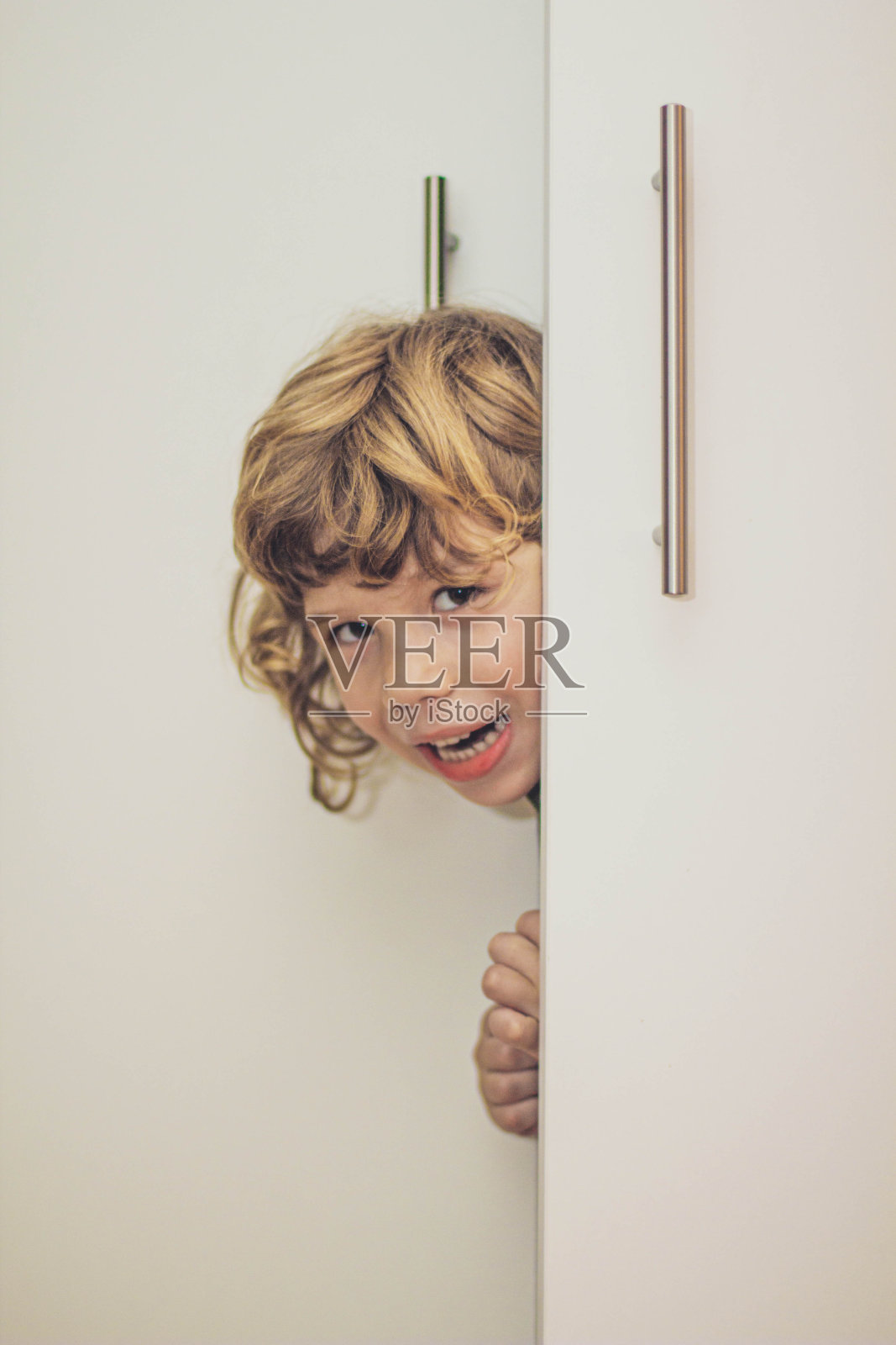 小男孩藏在衣柜里的照片照片摄影图片