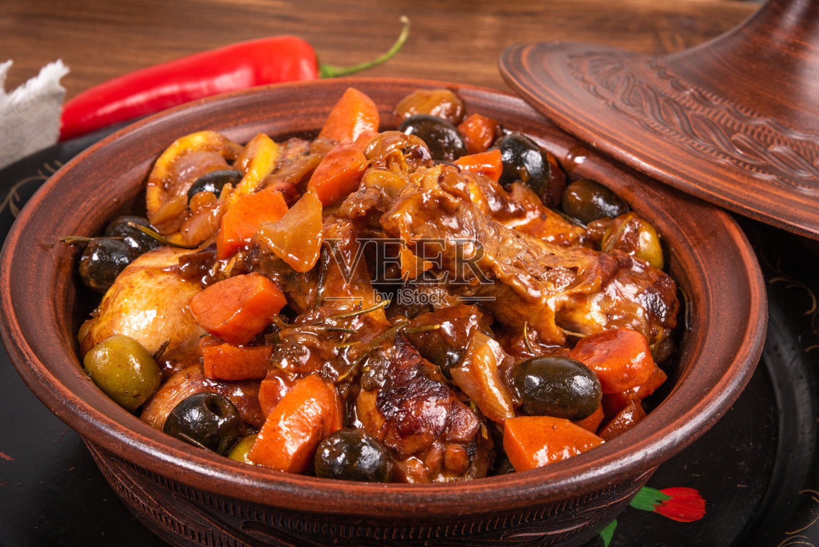 准备好的阿尔及利亚塔吉鸡配橄榄和辣酱蔬菜放在一张木桌上，俯视图，特写照片摄影图片