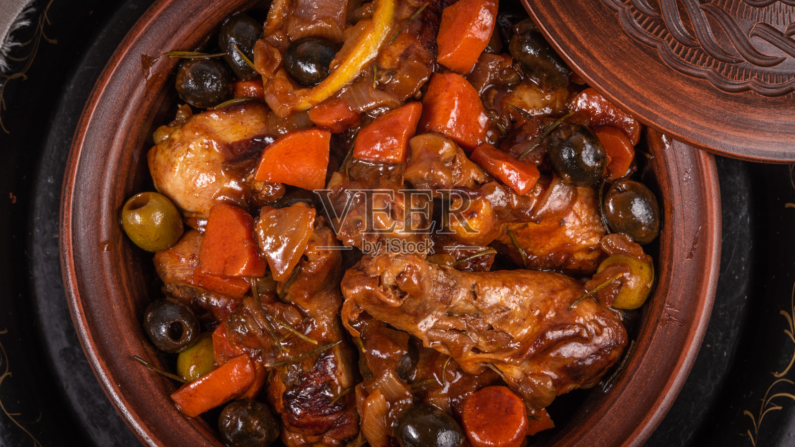 准备好的阿尔及利亚塔吉鸡配橄榄和辣酱蔬菜放在一张木桌上，俯视图，特写照片摄影图片