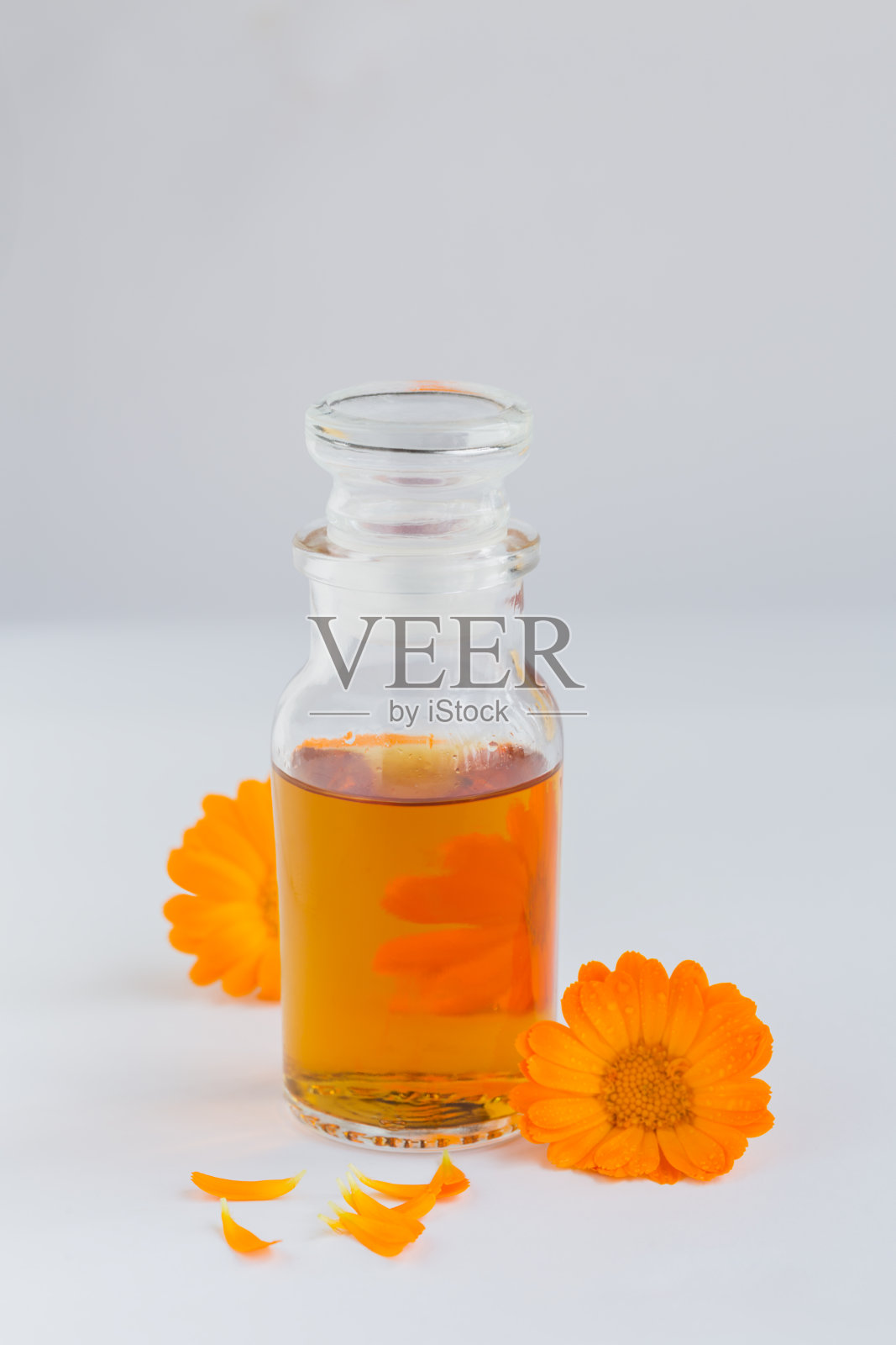 天然化妆品油，酊剂或输液与金盏花在白色背景。健康的皮肤护理。香薰、水疗和健康概念照片摄影图片