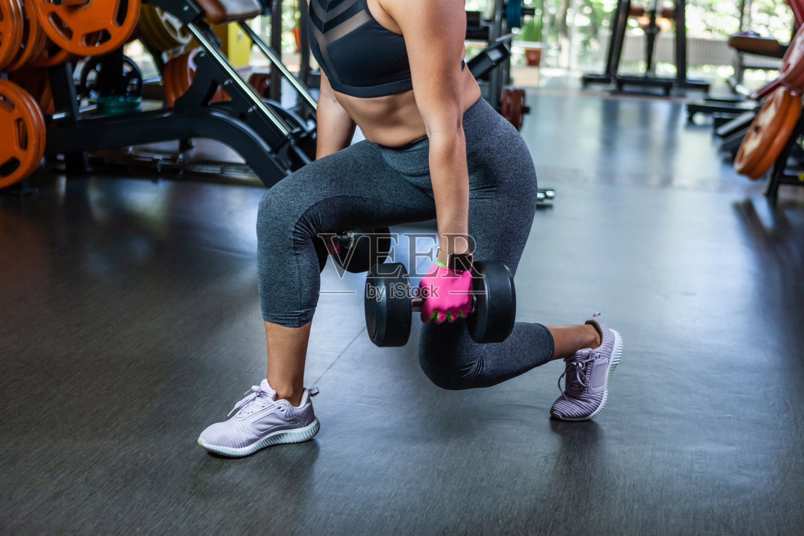 身体健康的女人在锻炼，手里拿着哑铃。在健身房练哑铃，腿部锻炼照片摄影图片