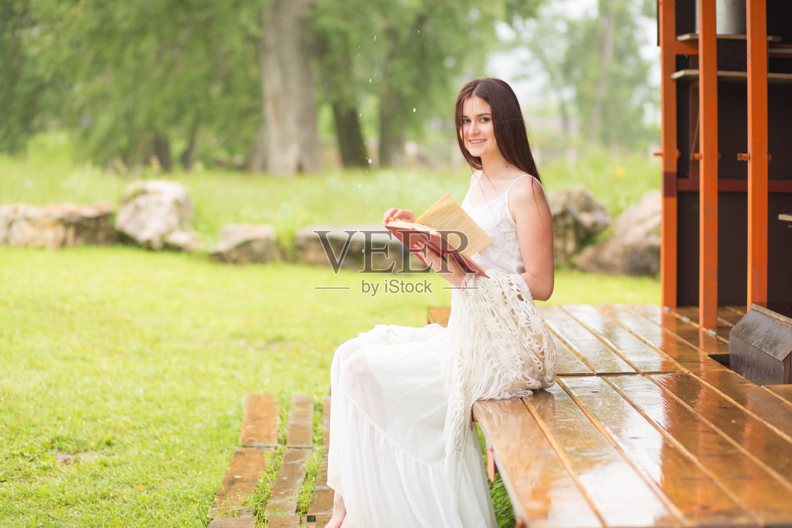 穿白衣服的漂亮女人读书。女孩坐在阳台上照片摄影图片