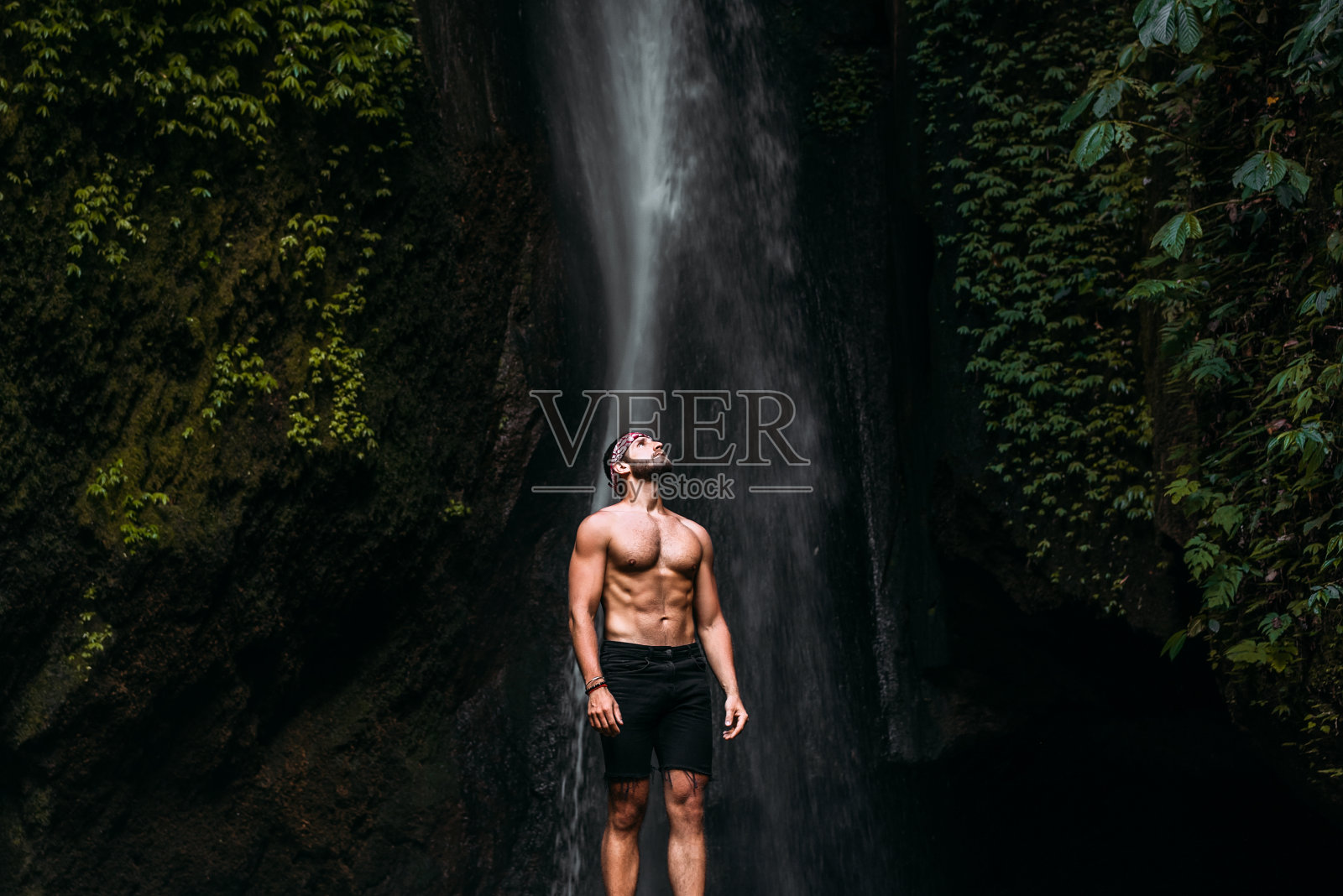 瀑布边一个体格健壮的男人。一个人周游世界。瀑布那边的人。去印度尼西亚的巴厘岛旅游。孤独的旅行者。本空间照片摄影图片