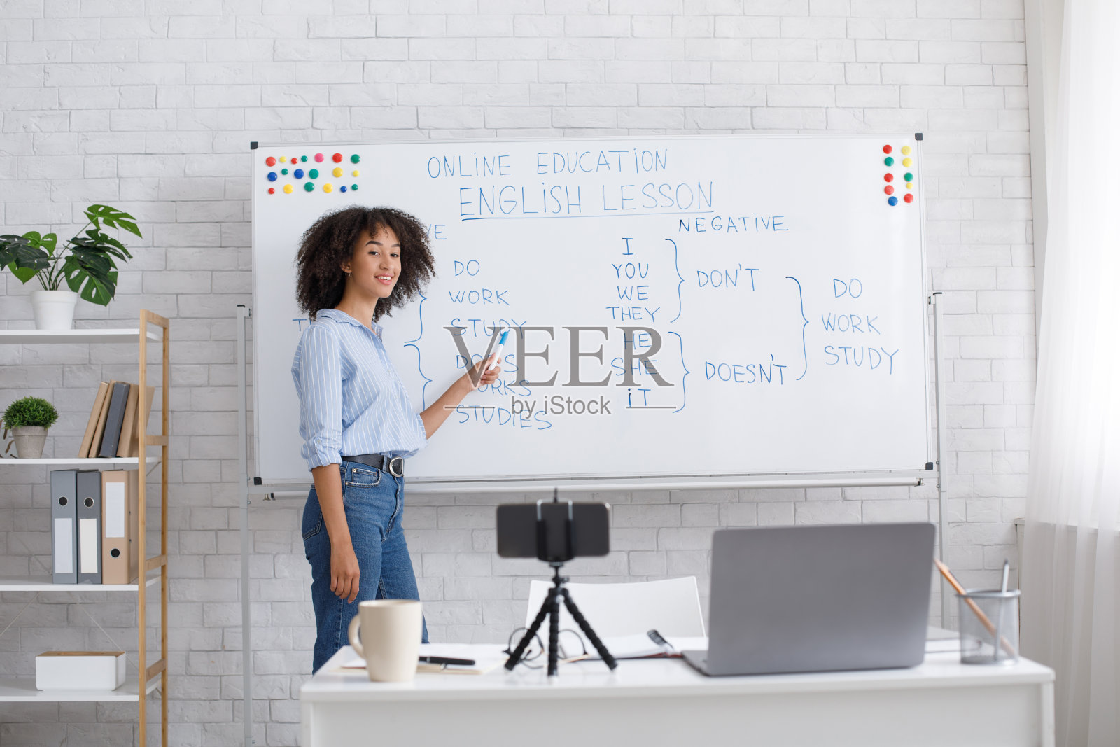 在线教育和英语课。友好的非裔美国妇女指着黑板照片摄影图片