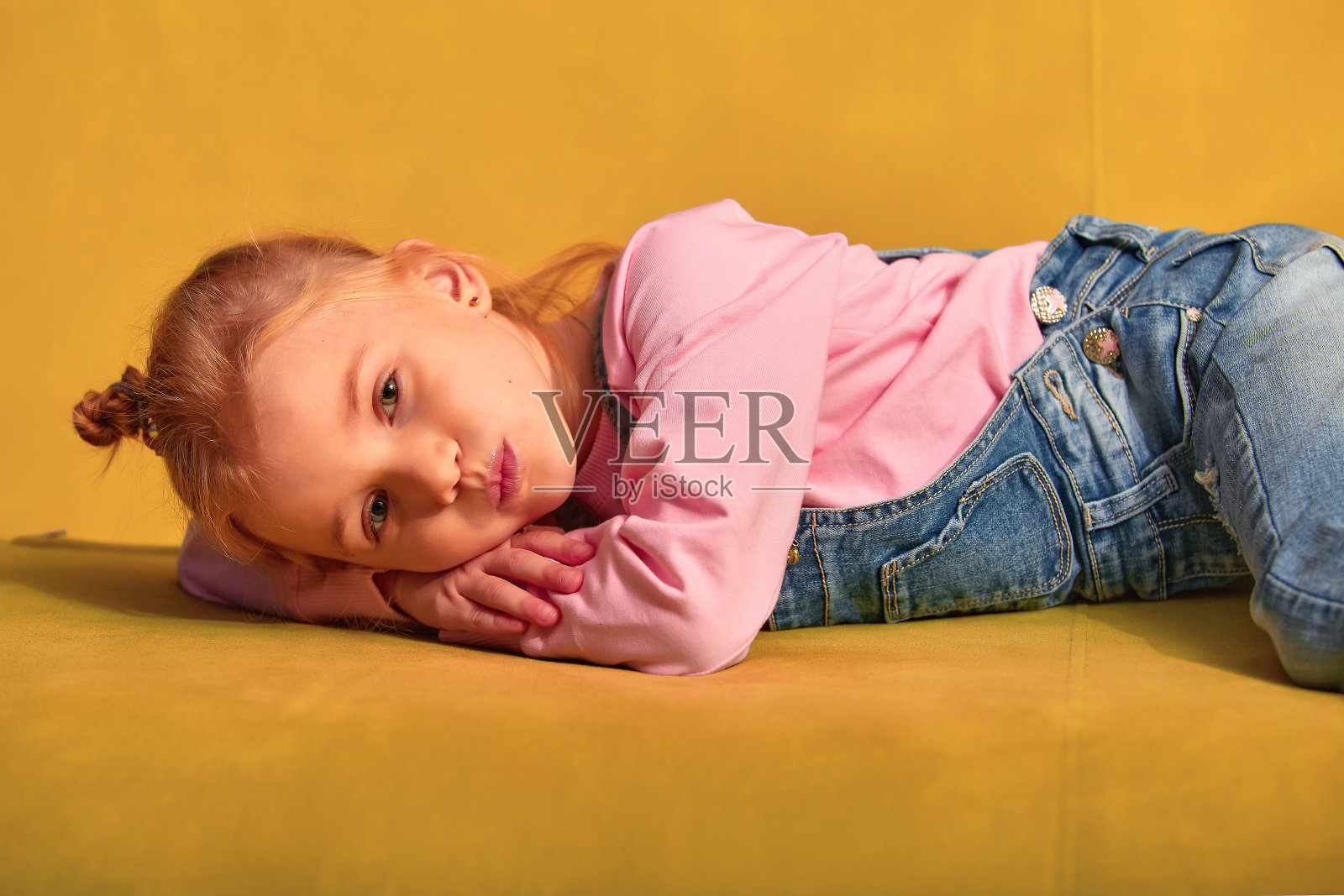 美国或欧洲小女孩的生活方式。微笑的女孩躺在家里的沙发上。儿童生活理念照片摄影图片