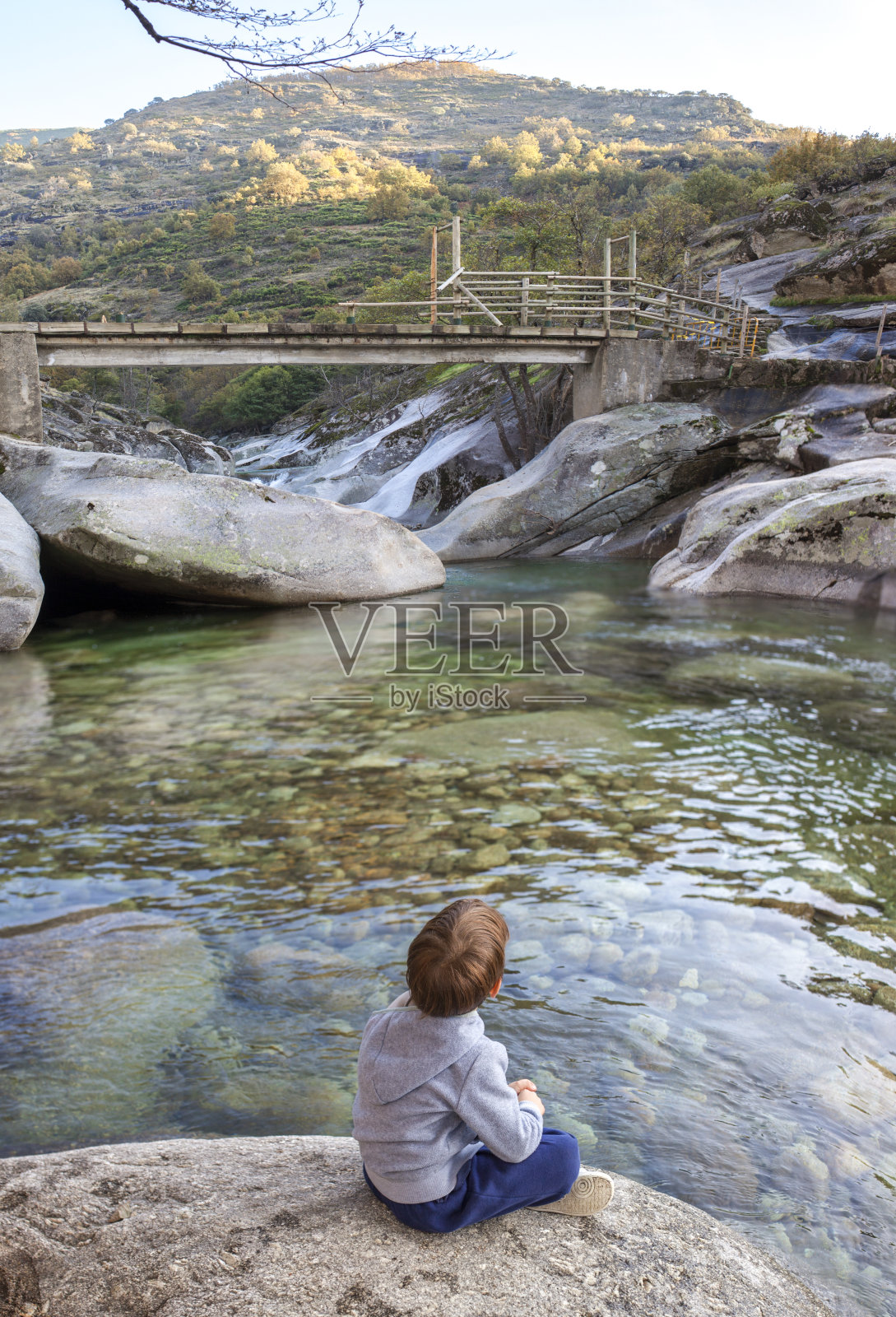 一个小男孩坐在地狱峡谷自然保护区的洛斯皮罗尼斯峡谷的河边照片摄影图片