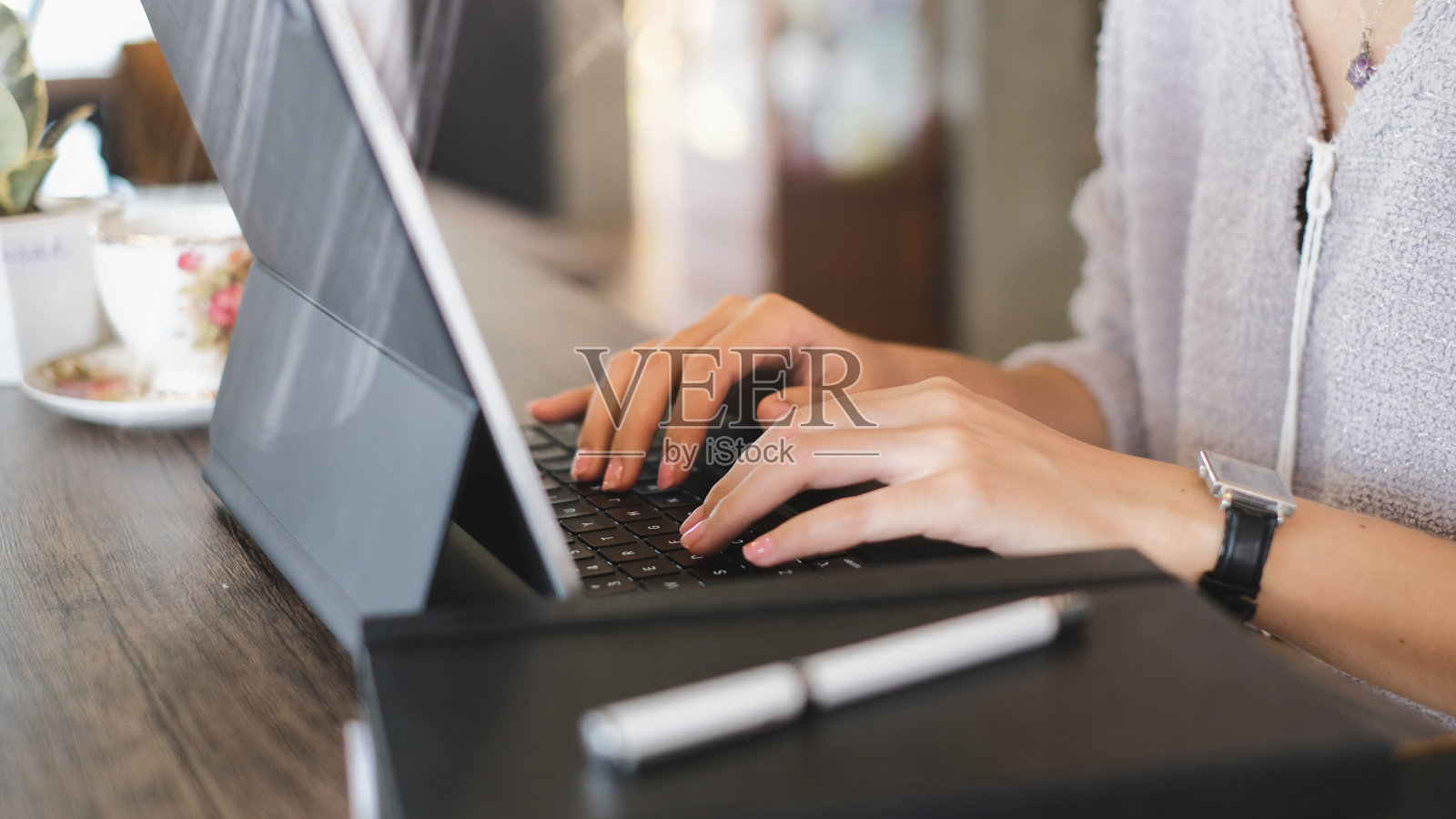 在木桌上的电脑笔记本电脑键盘上打字的年轻女性自由职业者的镜头。照片摄影图片