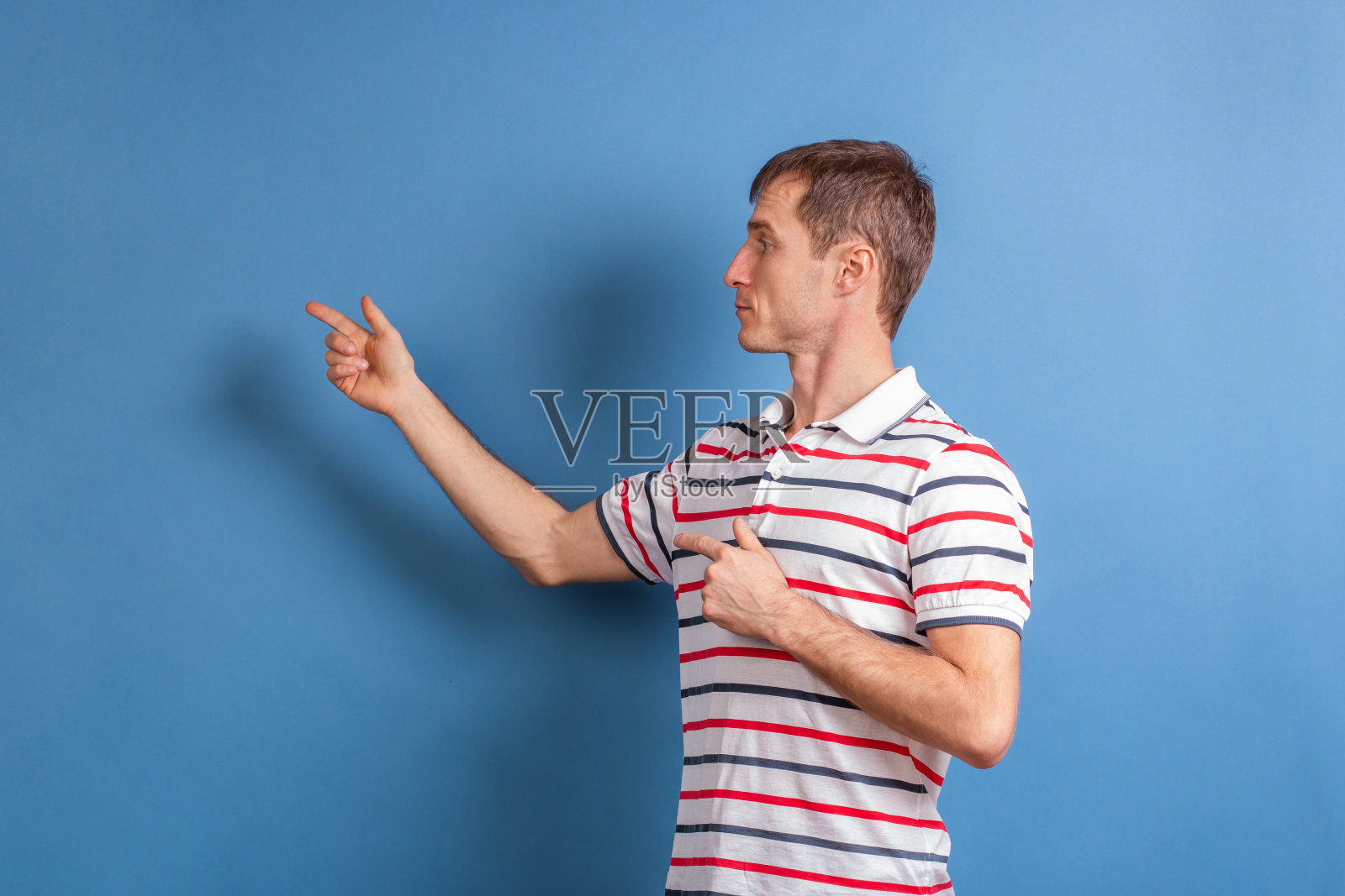 一位男老师展示了墙上蓝色背景的东西。年轻人用手指着文本。照片摄影图片