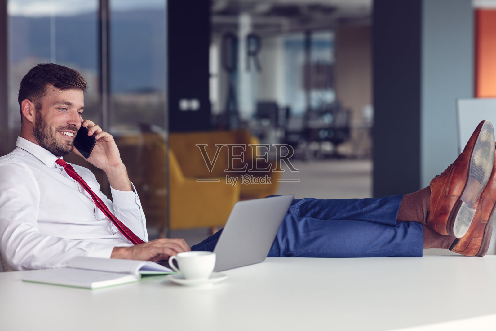 在办公室里使用笔记本电脑和智能手机的商人照片摄影图片