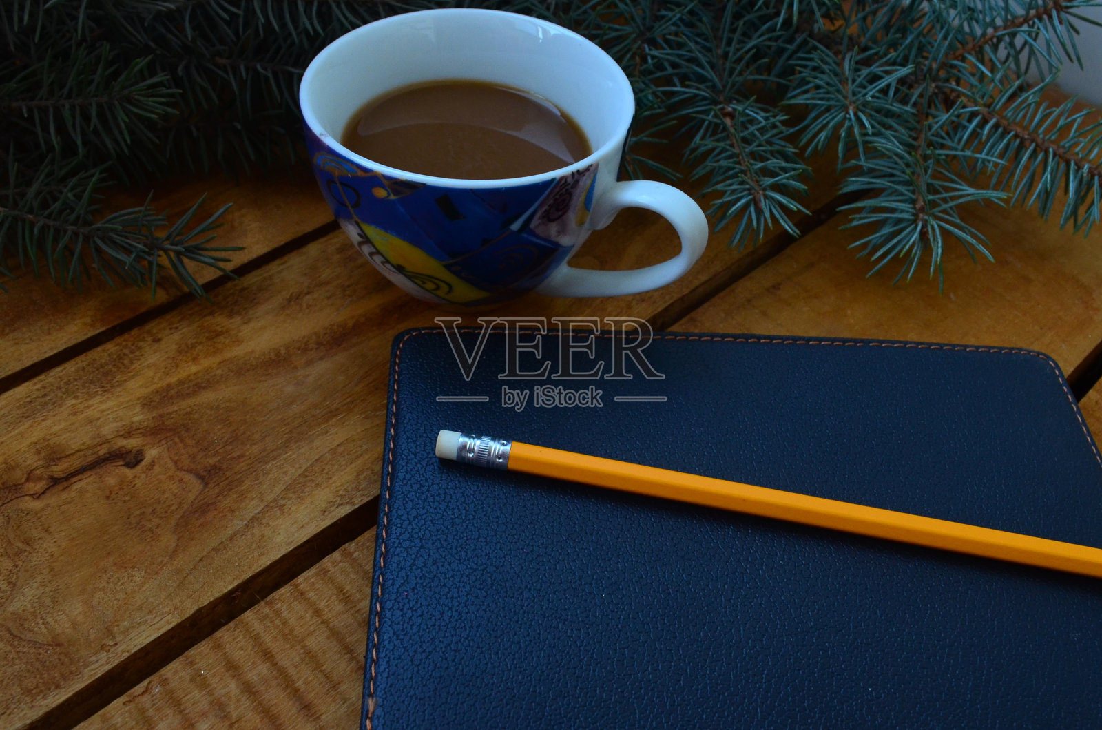 一个咖啡杯，一个黑色笔记本，一棵圣诞树和一支铅笔。办公用品，箱子，计划。照片摄影图片