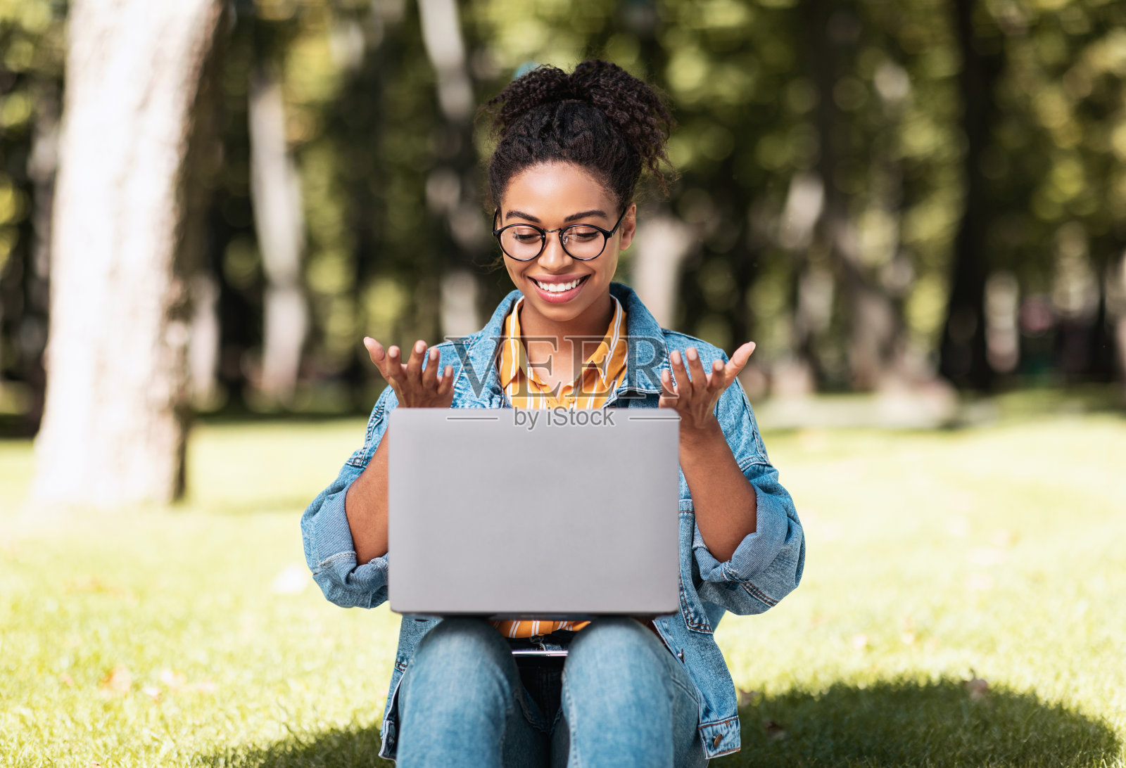 坐在外面用笔记本电脑打视频电话的快活的非洲女士照片摄影图片