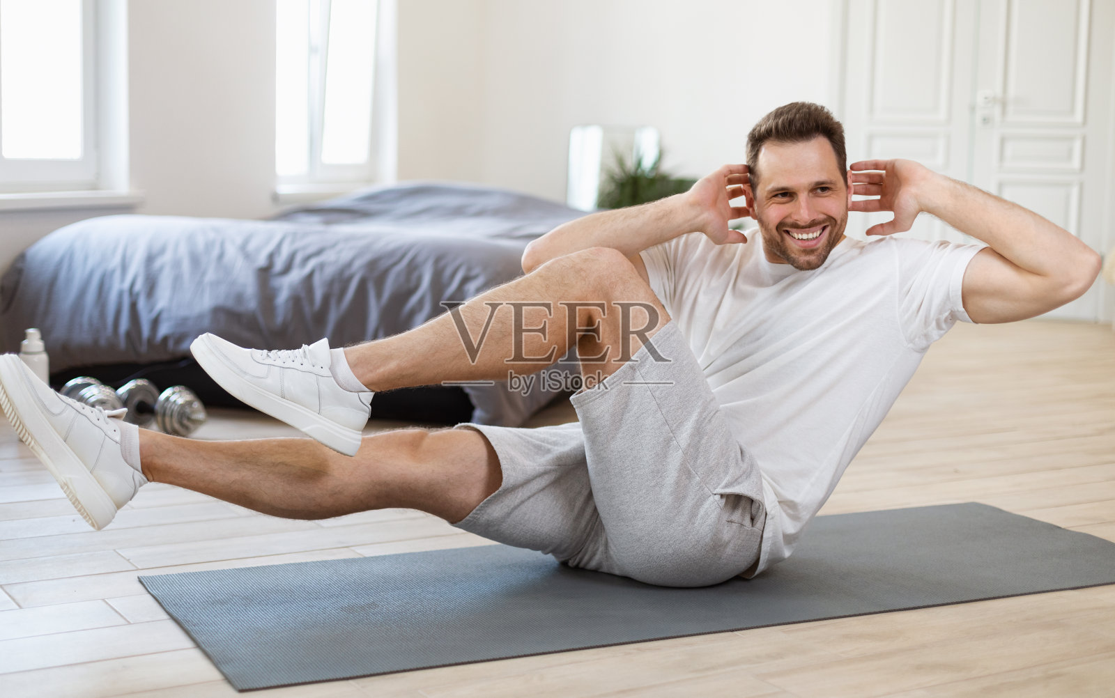 在家里垫子上做膝盖到肘部仰卧起坐的运动男子照片摄影图片
