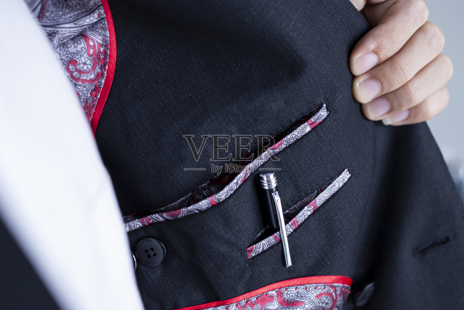 黑色西装里面装钢笔的口袋。拿着衬衫的人的手去看衣服里面的口袋。照片摄影图片