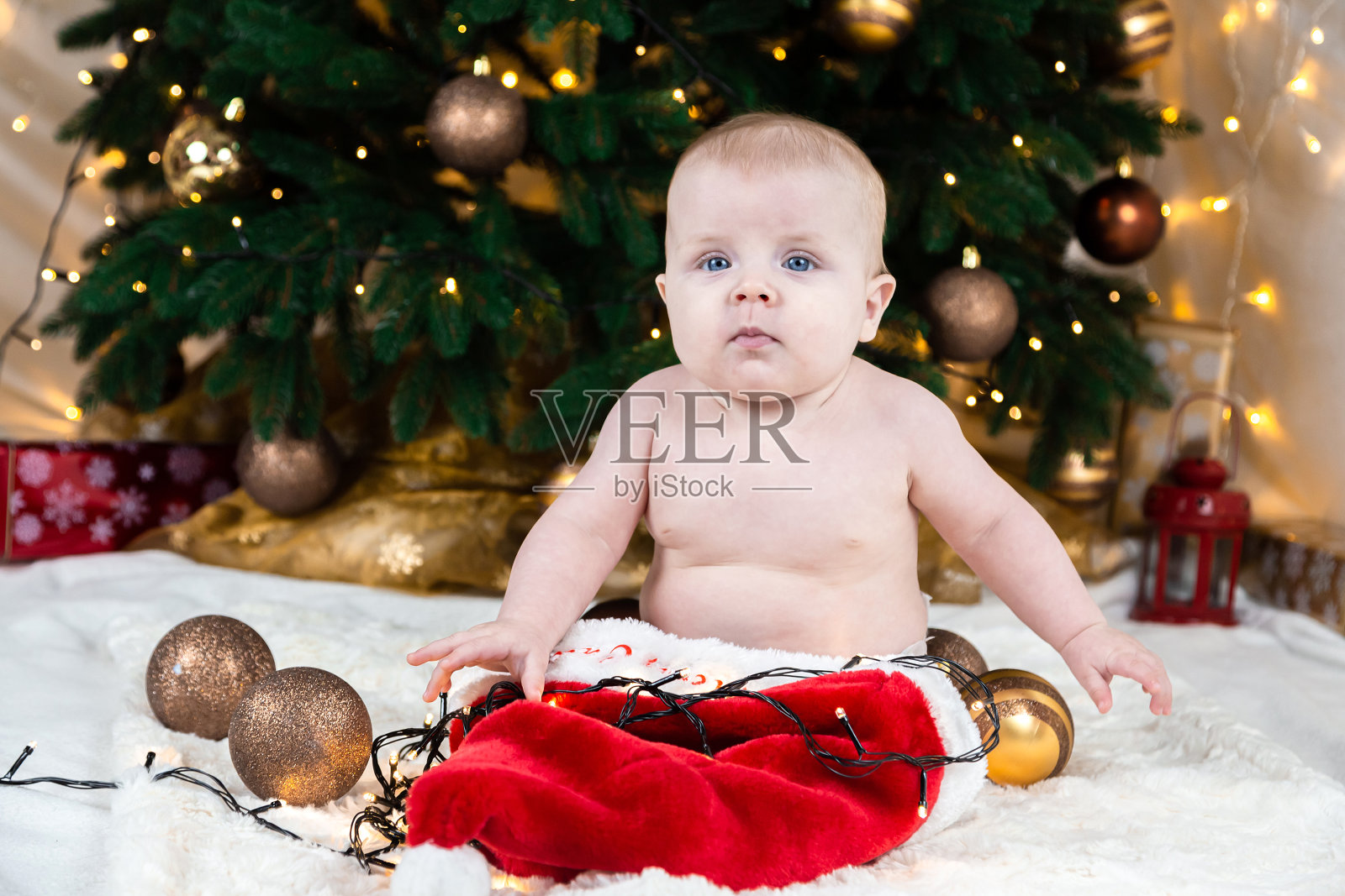 可爱的婴儿没有衣服的圣诞老人帽上的背景圣诞球照片摄影图片