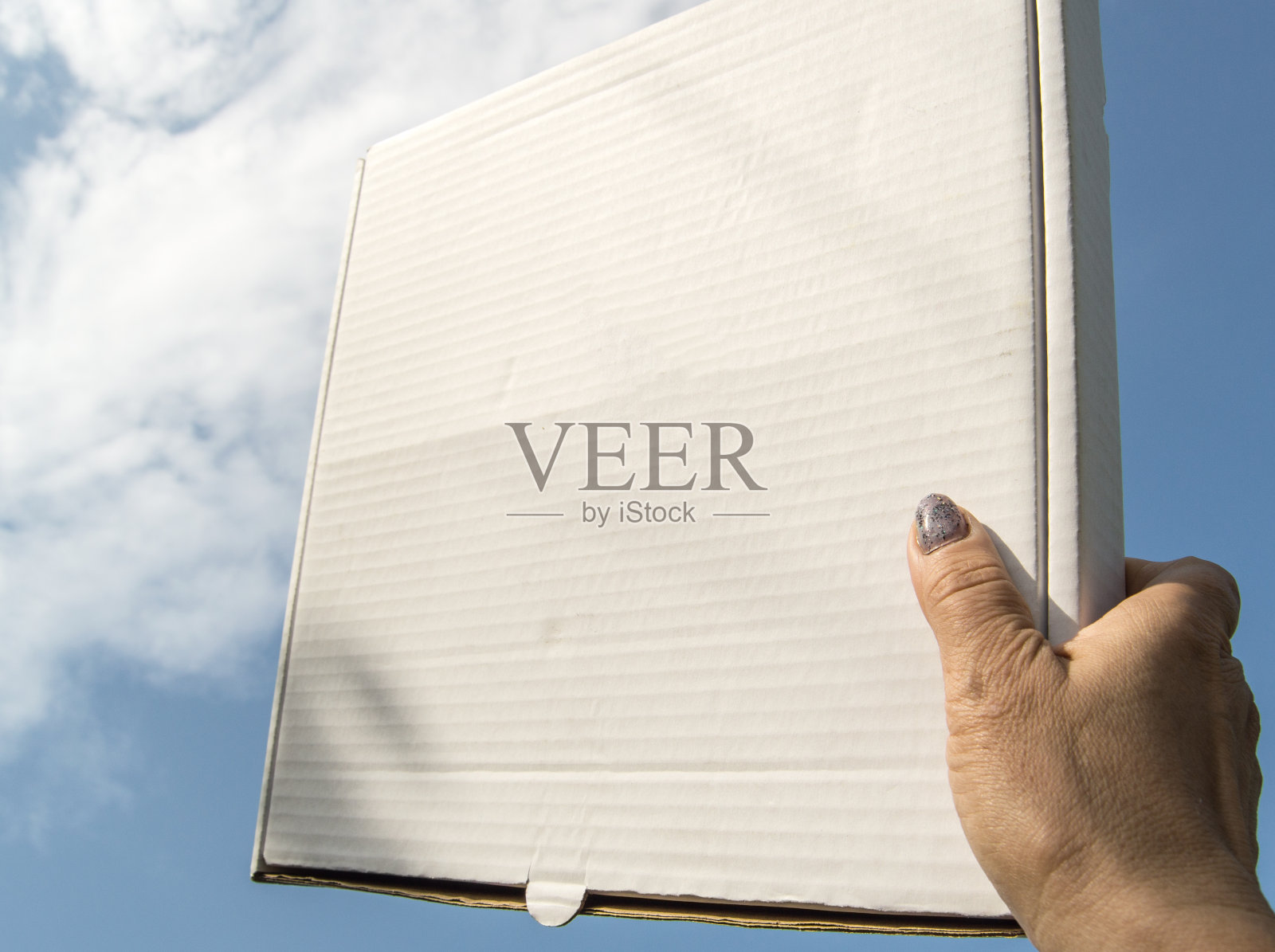 一个女人的手拿着一个白色的硬纸板盒子，里面有一个蓝色的天空背景，模板，模型照片摄影图片