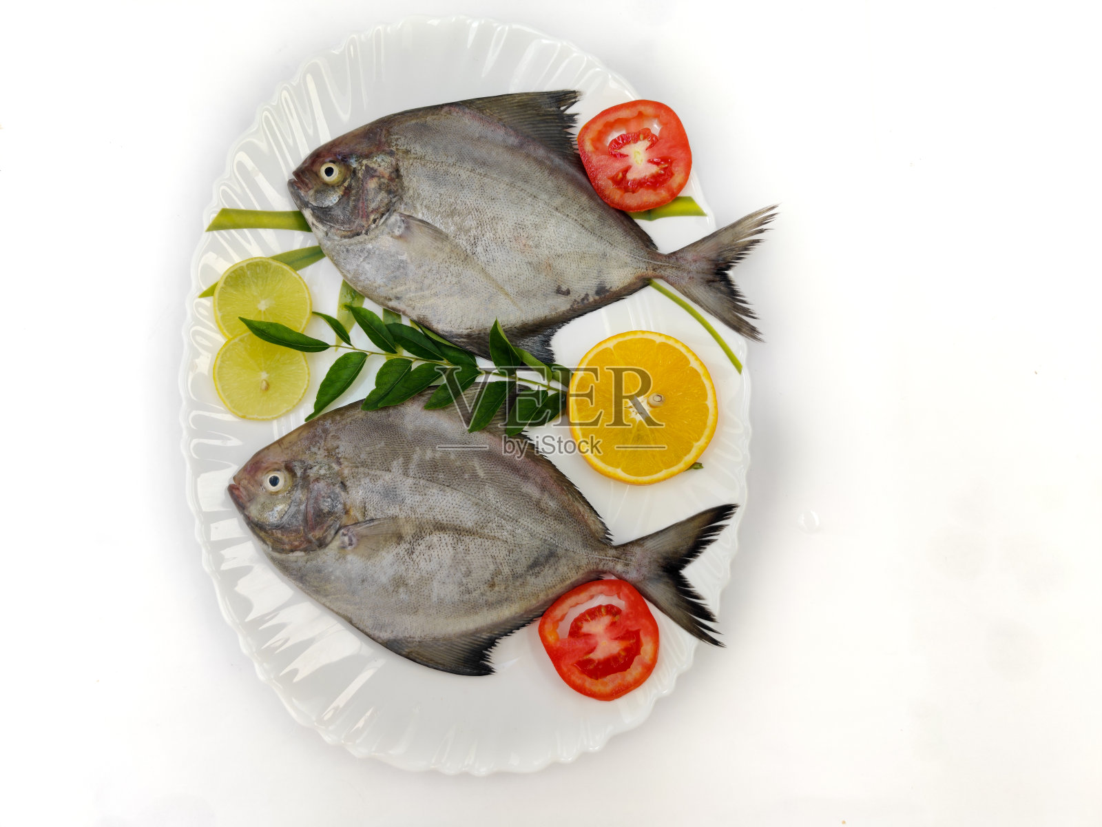 用蔬菜和香草装饰的黑鲳鱼。照片摄影图片