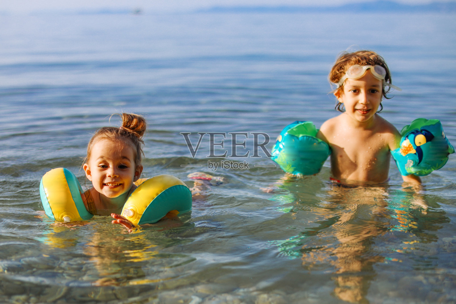 快乐的笑着蹒跚学步的女孩与朋友在海里玩得开心照片摄影图片