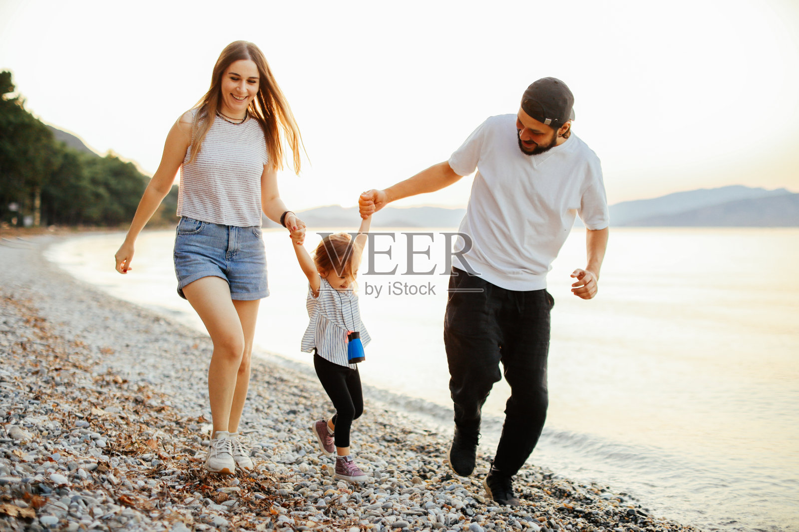 在美丽的夏日，幸福的一家人坐在沙滩上放松照片摄影图片