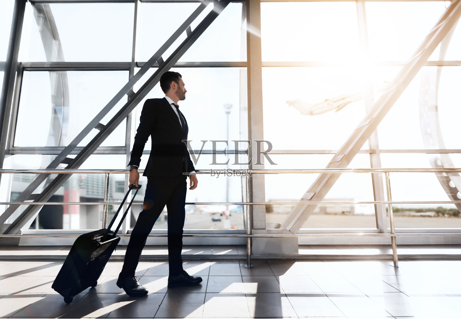 路过机场候机楼的商人，从窗口望出去照片摄影图片