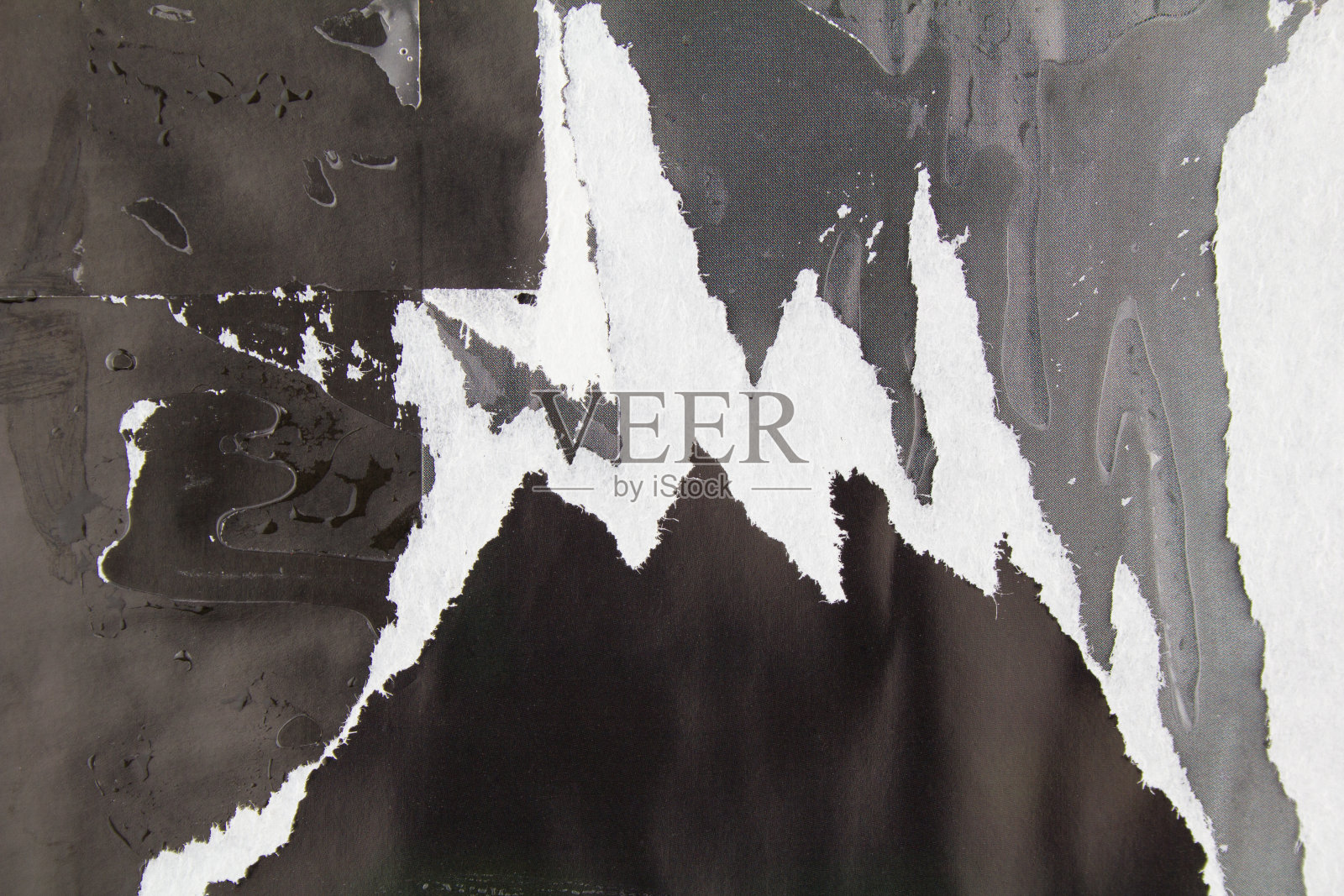 黑色和灰色撕破的杂志纸和脏的胶水痕迹和污渍。抽象的背景。照片摄影图片