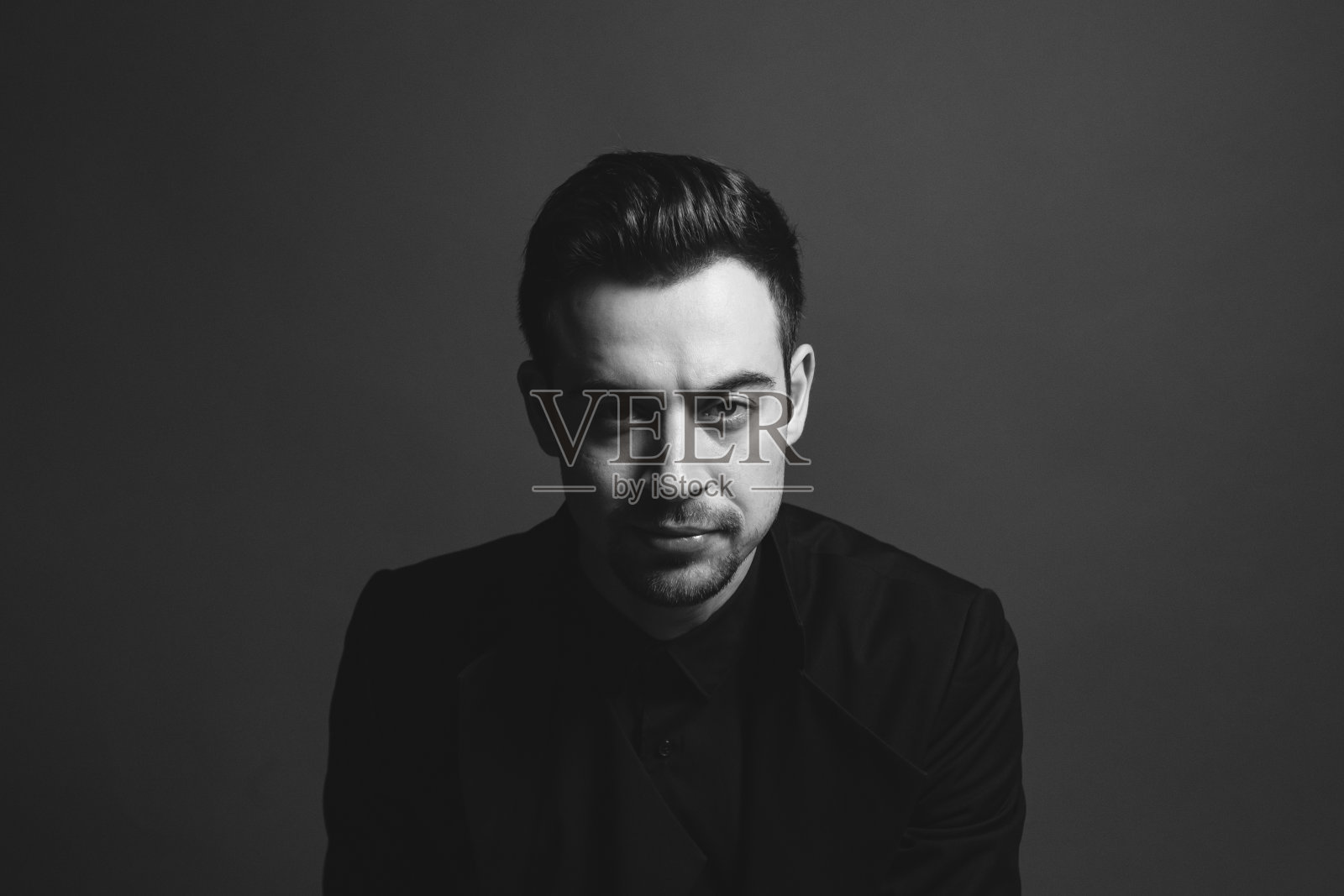 一个年轻男子在一个工作室的肖像在一个朴素的工作室背景黑色西装外套照片摄影图片