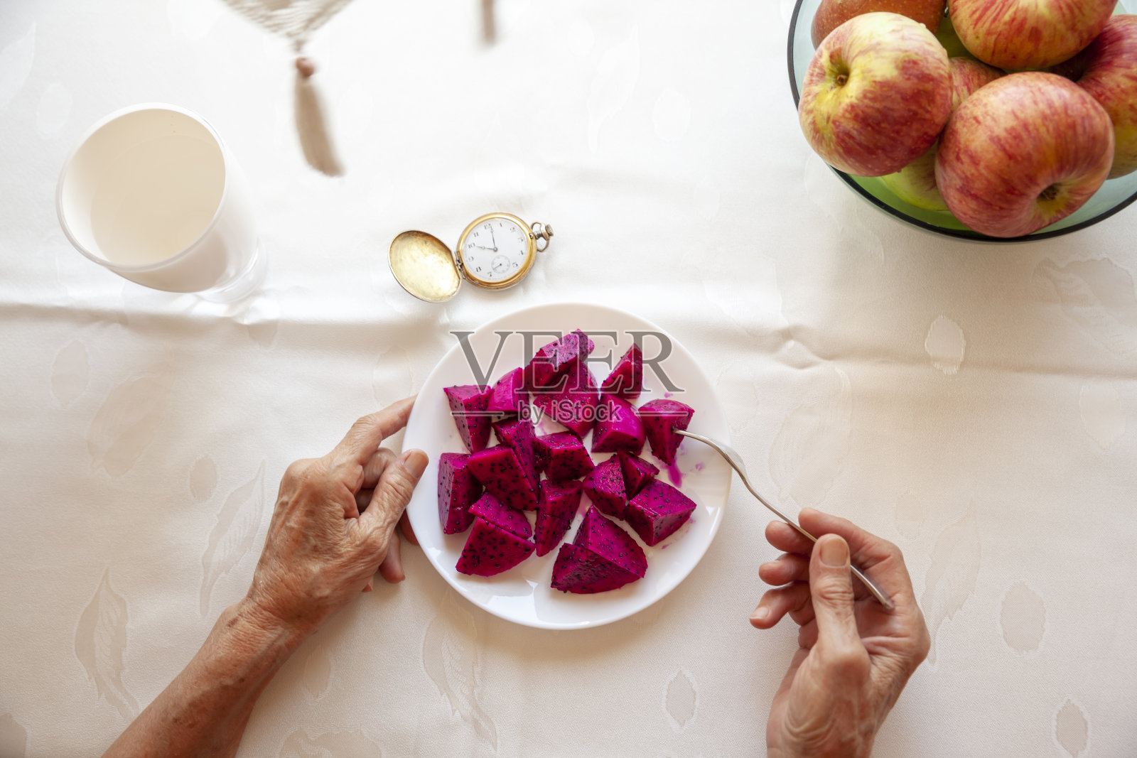 正在吃火龙果的年长妇女照片摄影图片