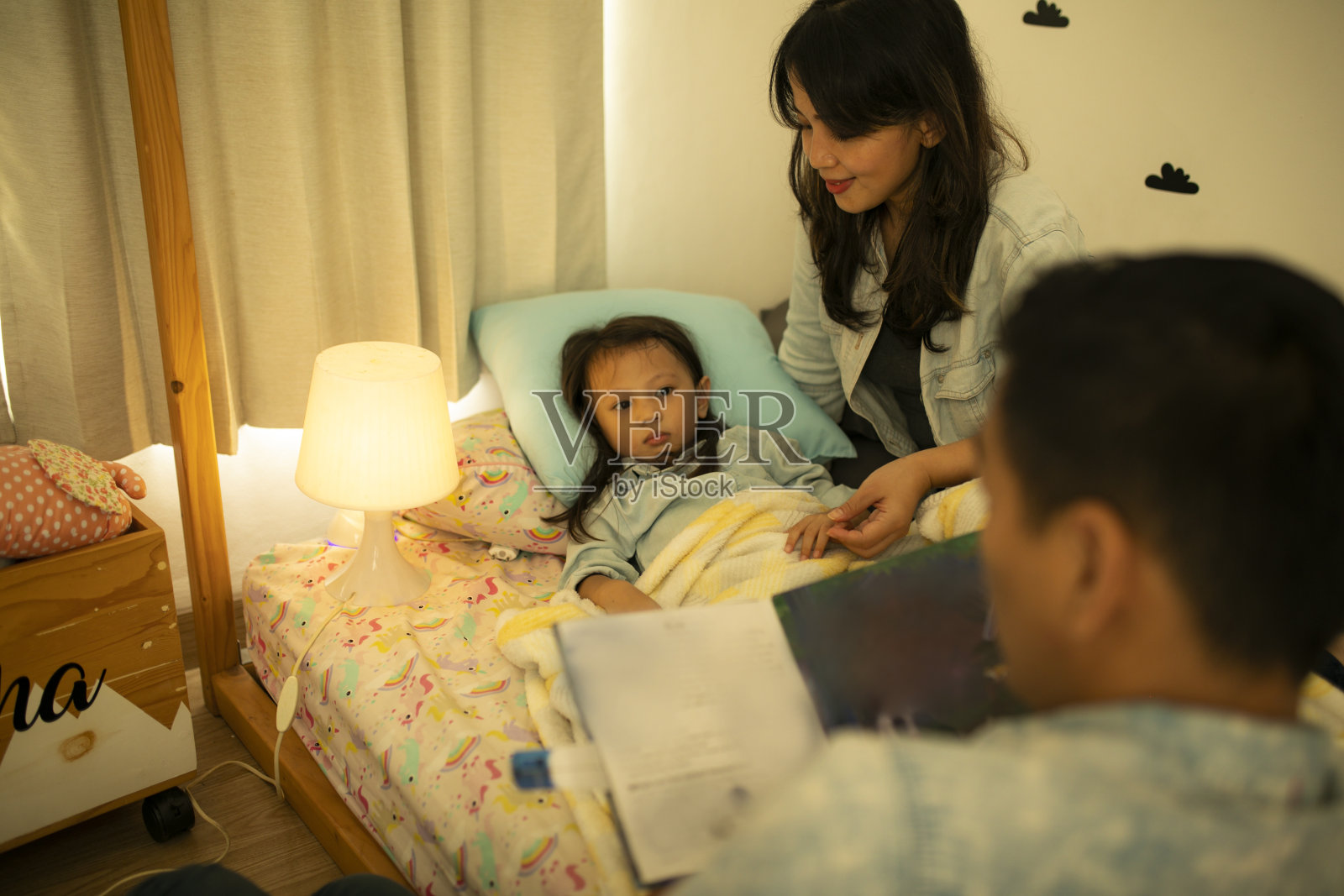 一张父母给女儿读睡前故事的照片照片摄影图片