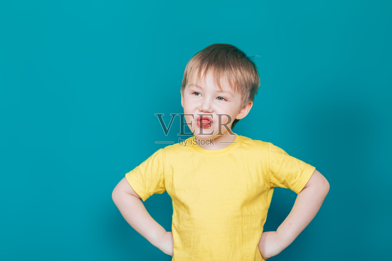 小男孩穿着黄色的t恤露出舌头照片摄影图片