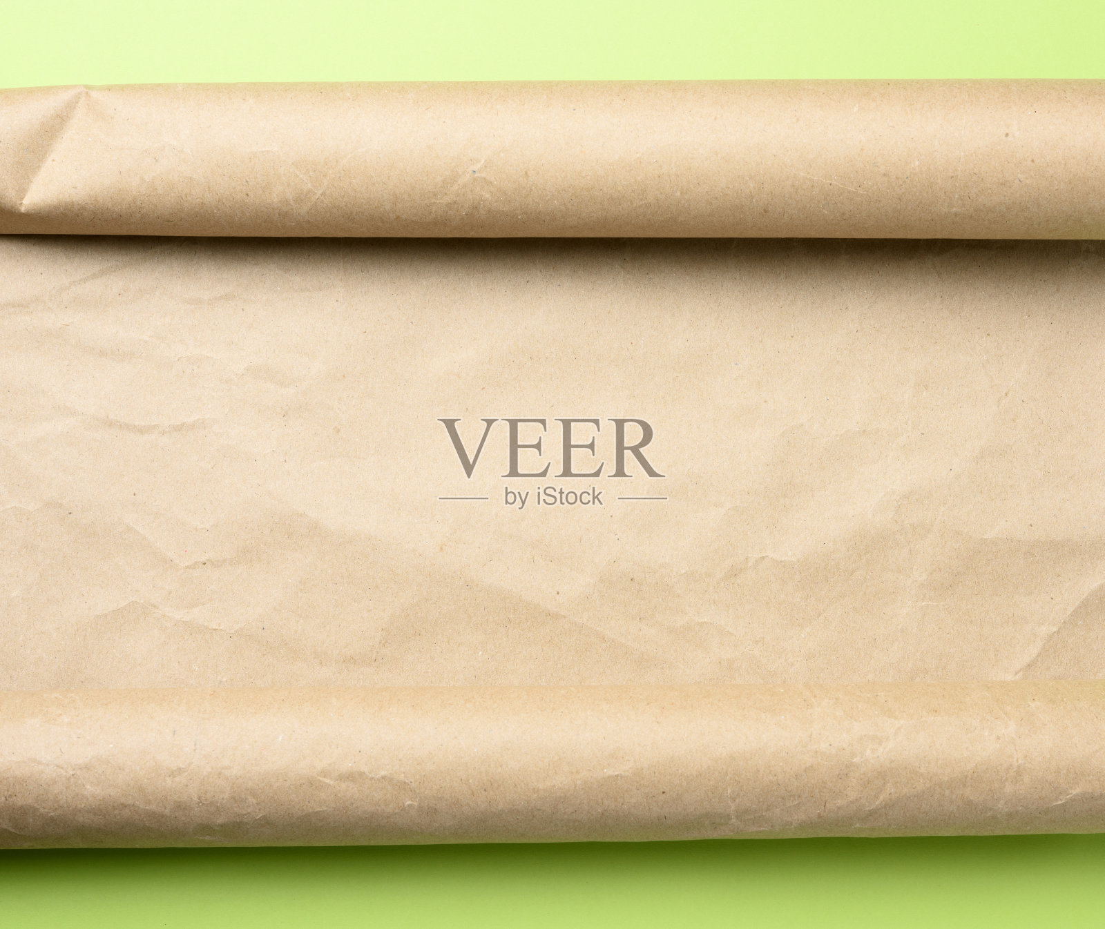 绿色背景的一卷棕色羊皮纸，照片摄影图片