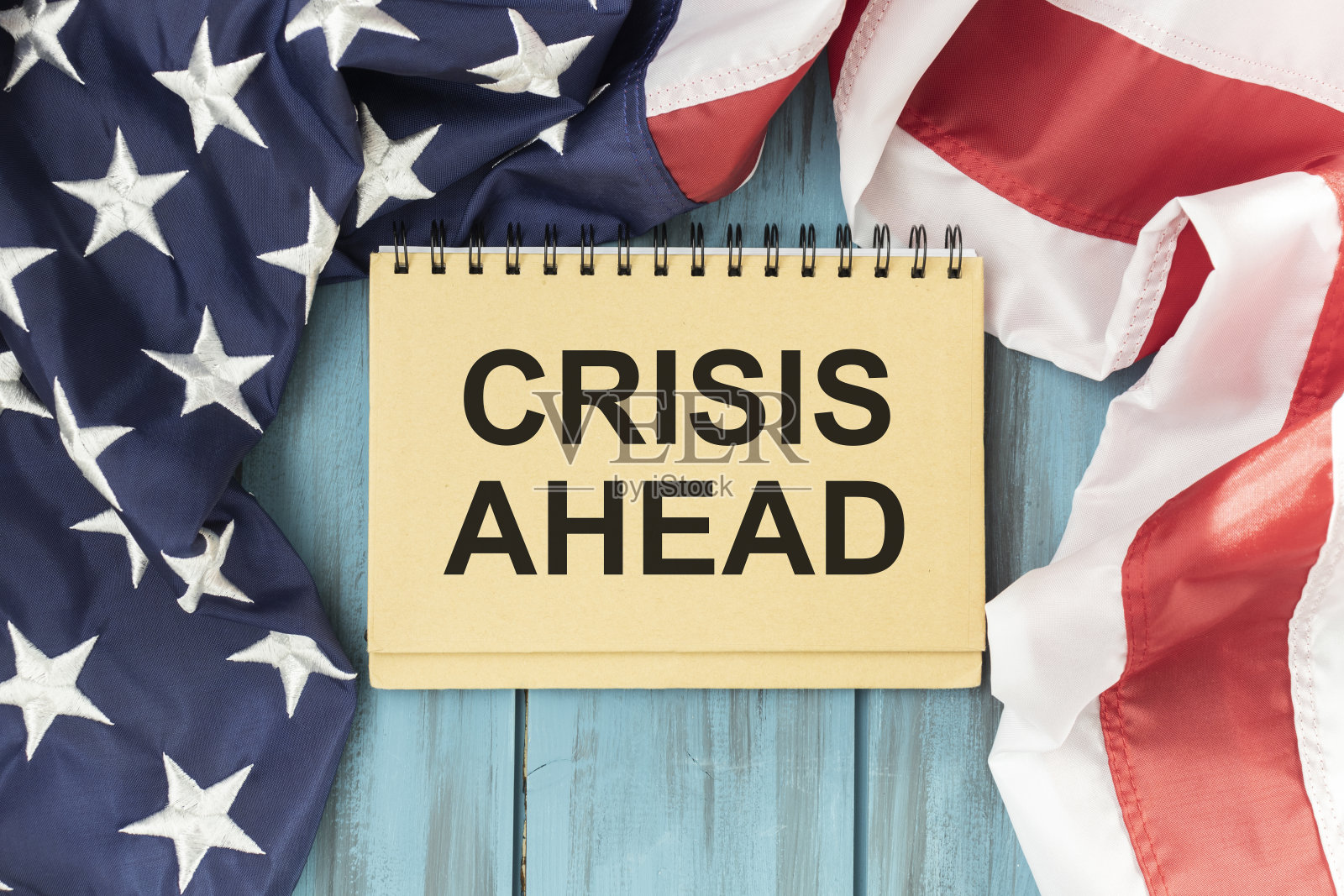 卡片上写着“危机在即”。美国国旗和木制背景照片摄影图片