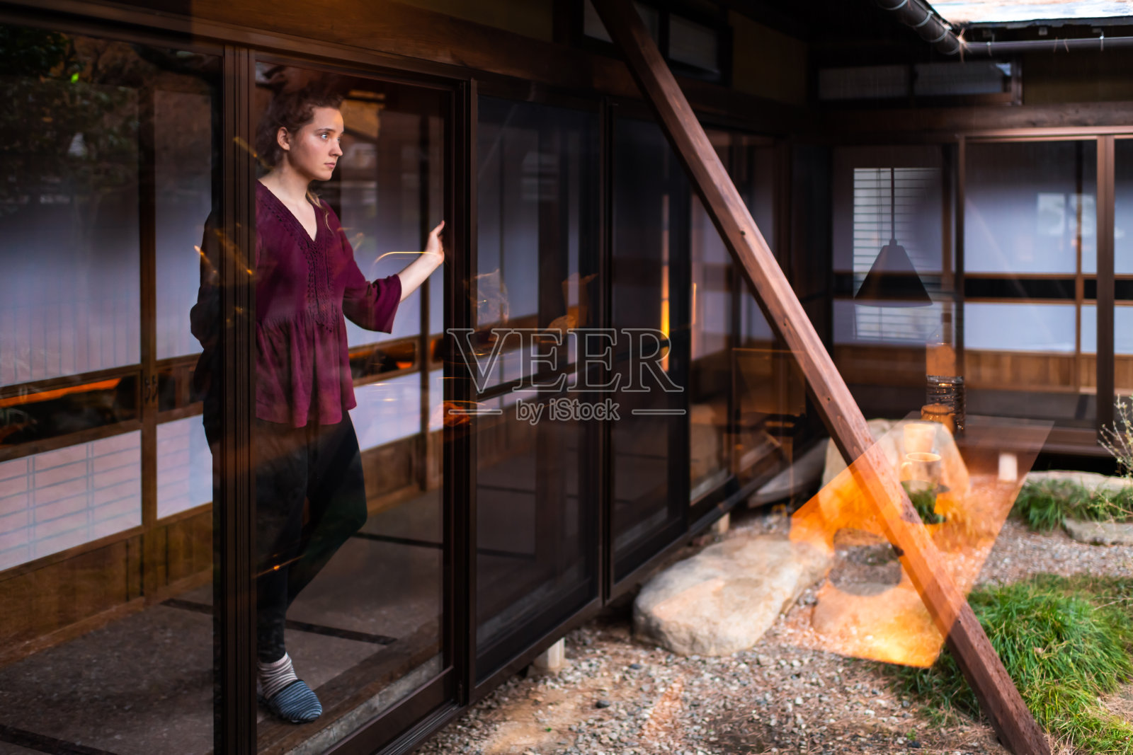 年轻女子站在小日本室内透过窗户推拉门看日本传统花园与砾石石头在房子照片摄影图片