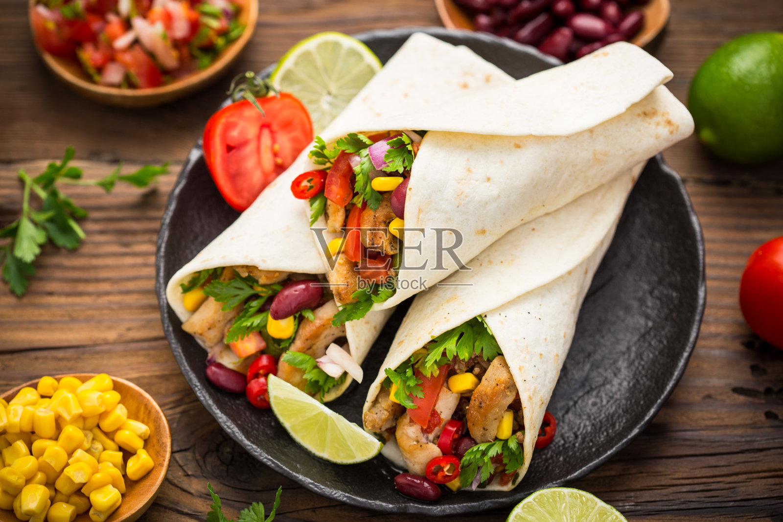 木桌上放着新鲜的玉米饼、鸡肉和蔬菜照片摄影图片