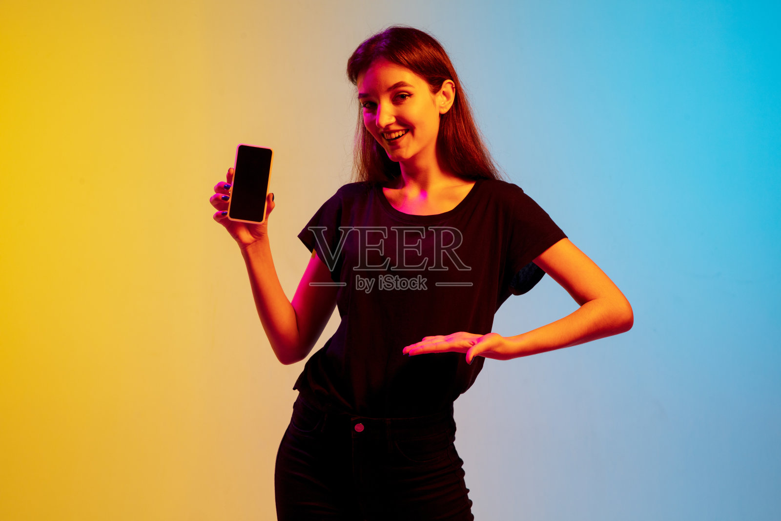 年轻的白人妇女的肖像在渐变蓝黄色的工作室背景霓虹灯照片摄影图片