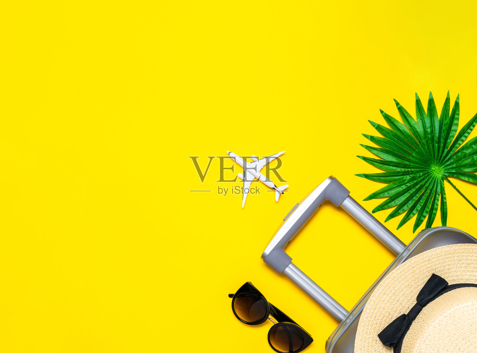 夏天背景表。手提箱、棕叶太阳镜、草帽、黄色背景上白色飞机的旅行构图。复制空间，暑假和商务旅行的概念。照片摄影图片