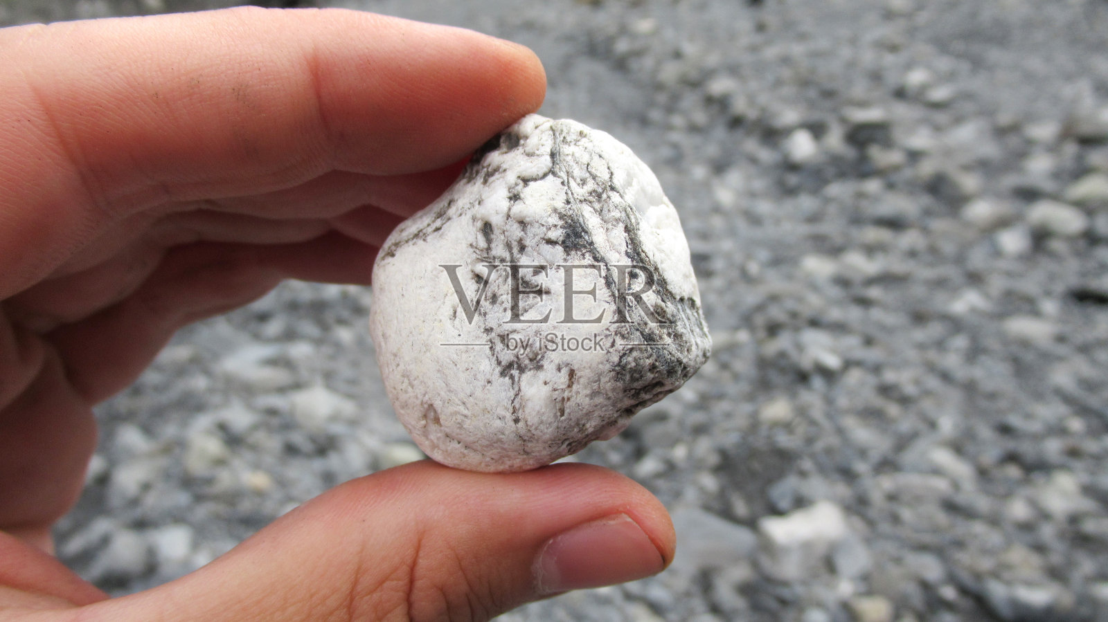 近距离的年轻男性的手拿着一个天然的河石在他的手照片摄影图片