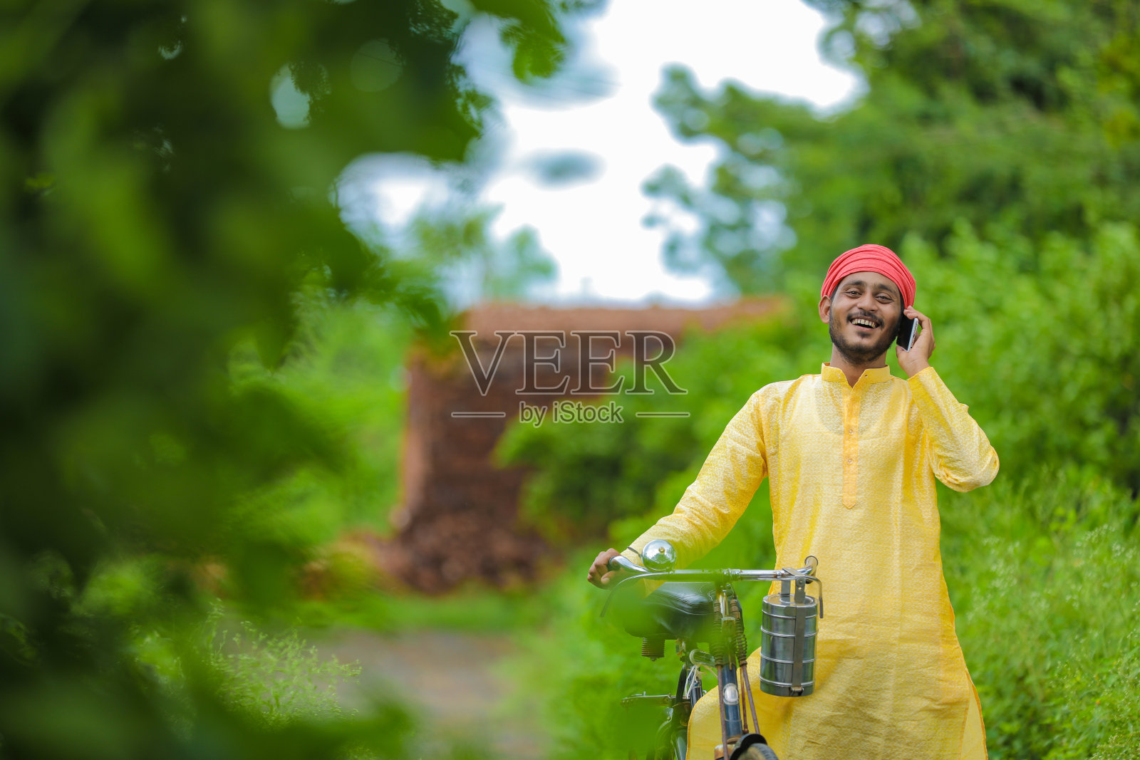 年轻的印度农民或工人骑着自行车和用手机工作照片摄影图片