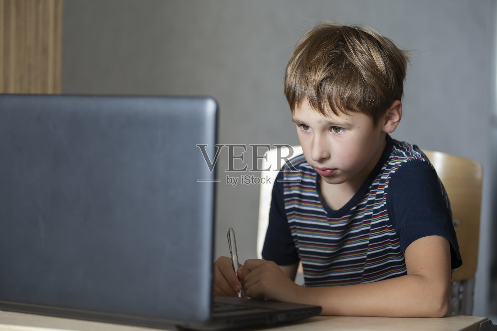 男生在家在线上课，社会距离期间隔离，自我隔离，网络教育理念。小学男孩在家用笔记本电脑。照片摄影图片