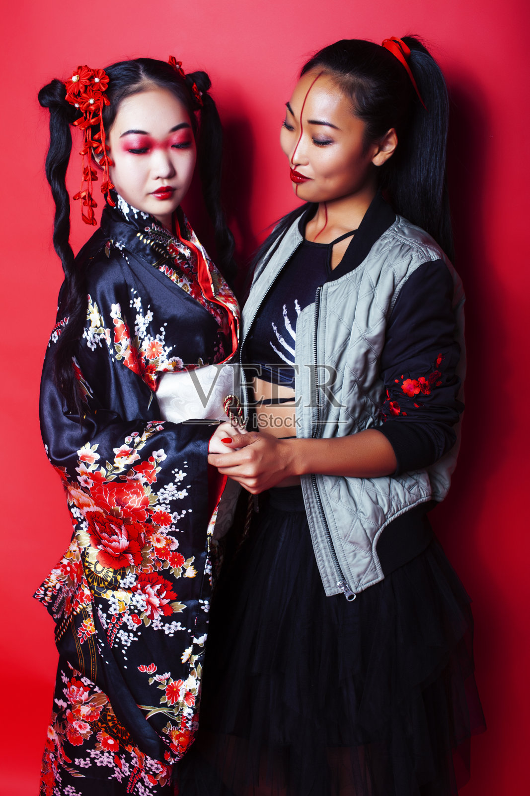 两个漂亮的艺妓朋友:现代亚洲女性和传统穿着和服摆出欢快的红色背景照片摄影图片