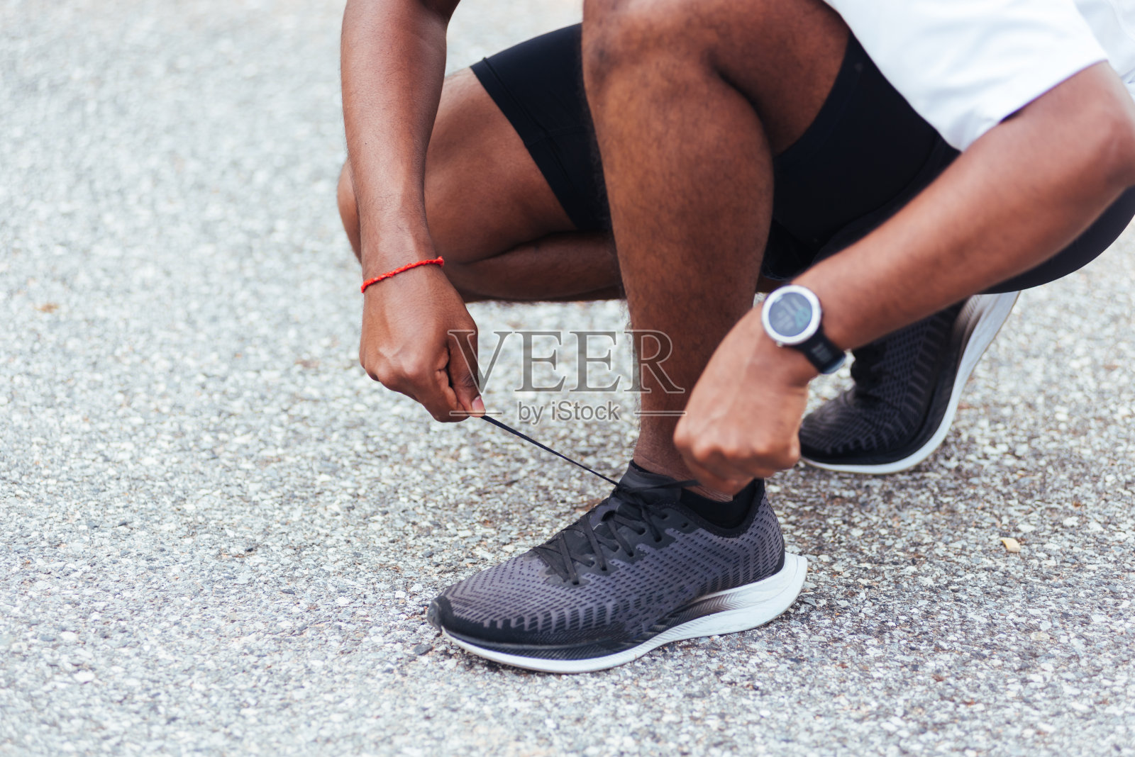 跑者黑人戴着手表坐着，他试着鞋带跑鞋照片摄影图片