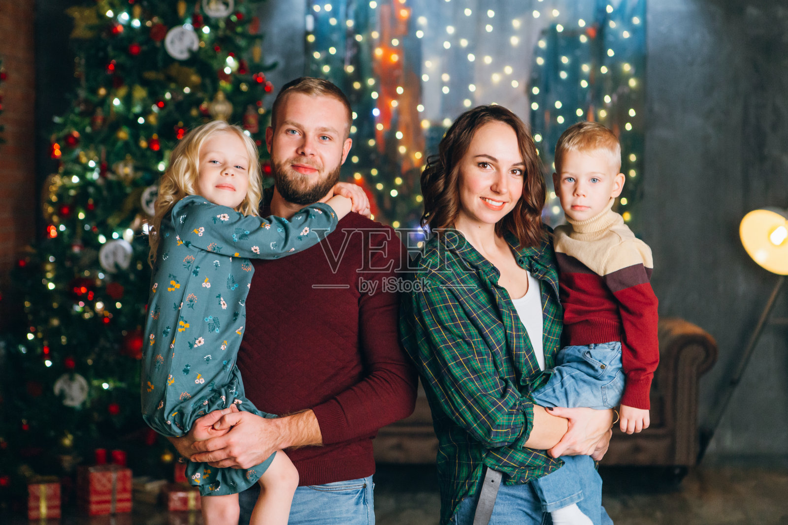 一个年轻的家庭和两个孩子在圣诞树旁照片摄影图片