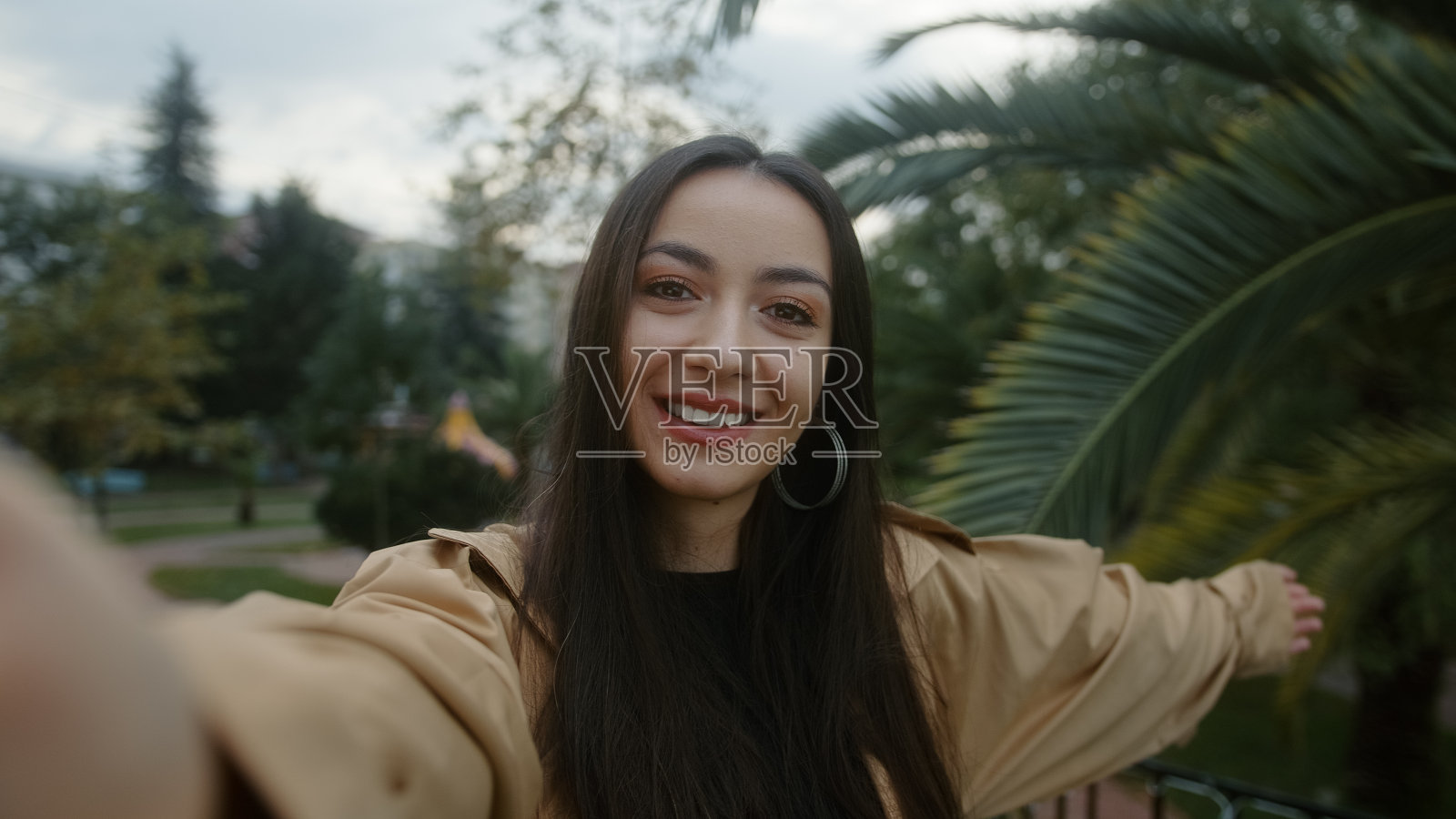 美丽的年轻微笑的脸女人拿着相机或手机在手里，她做视频电话或她正在为她的粉丝录制视频，她突然惊讶，视频电话和视频博主的概念照片摄影图片