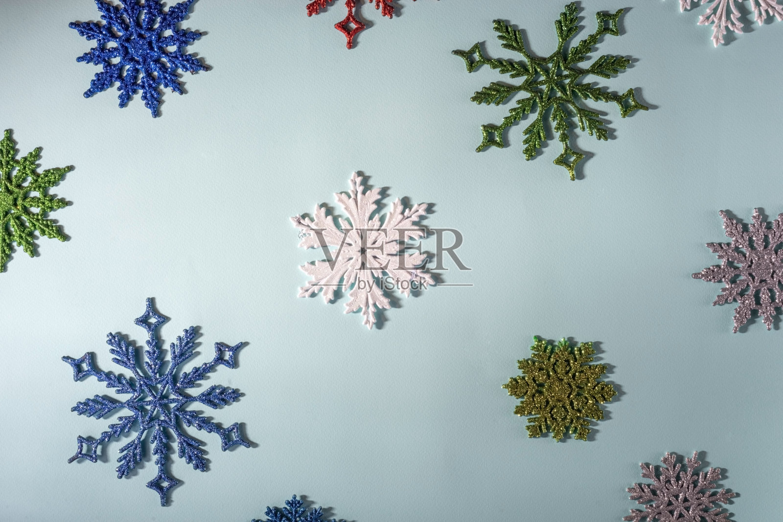 在蓝色的背景上放上五彩缤纷的圣诞雪花。从上面的观点照片摄影图片