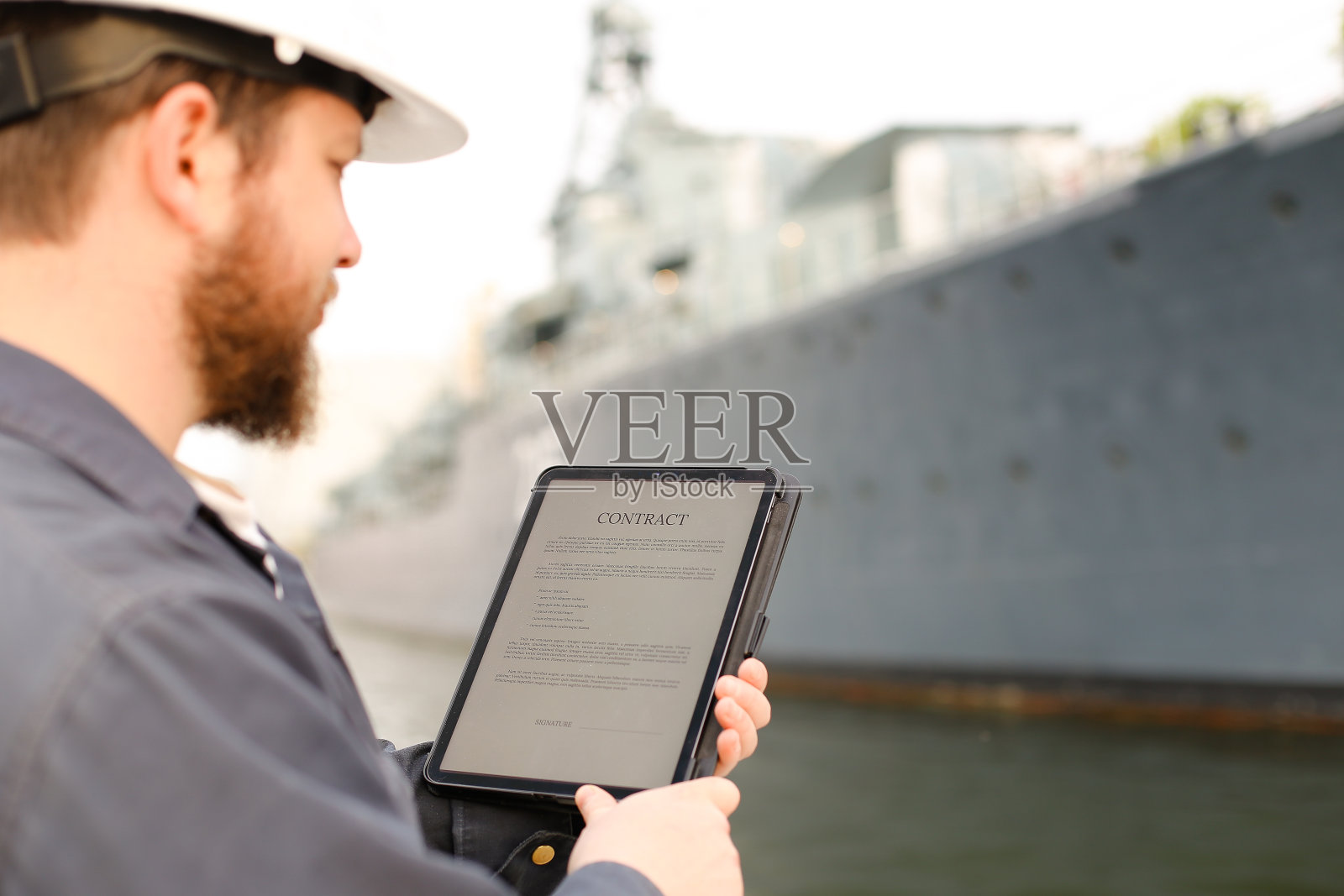 大副在后台船只附近的平板上阅读合同照片摄影图片