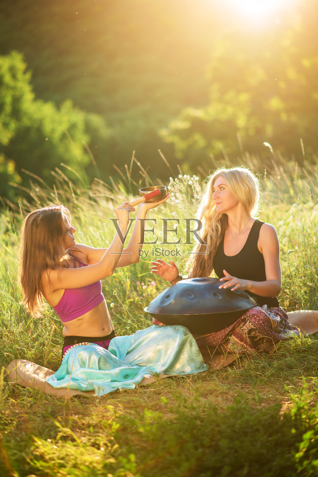 年轻女子用手盘弹琴唱歌。在日落时练习冥想照片摄影图片