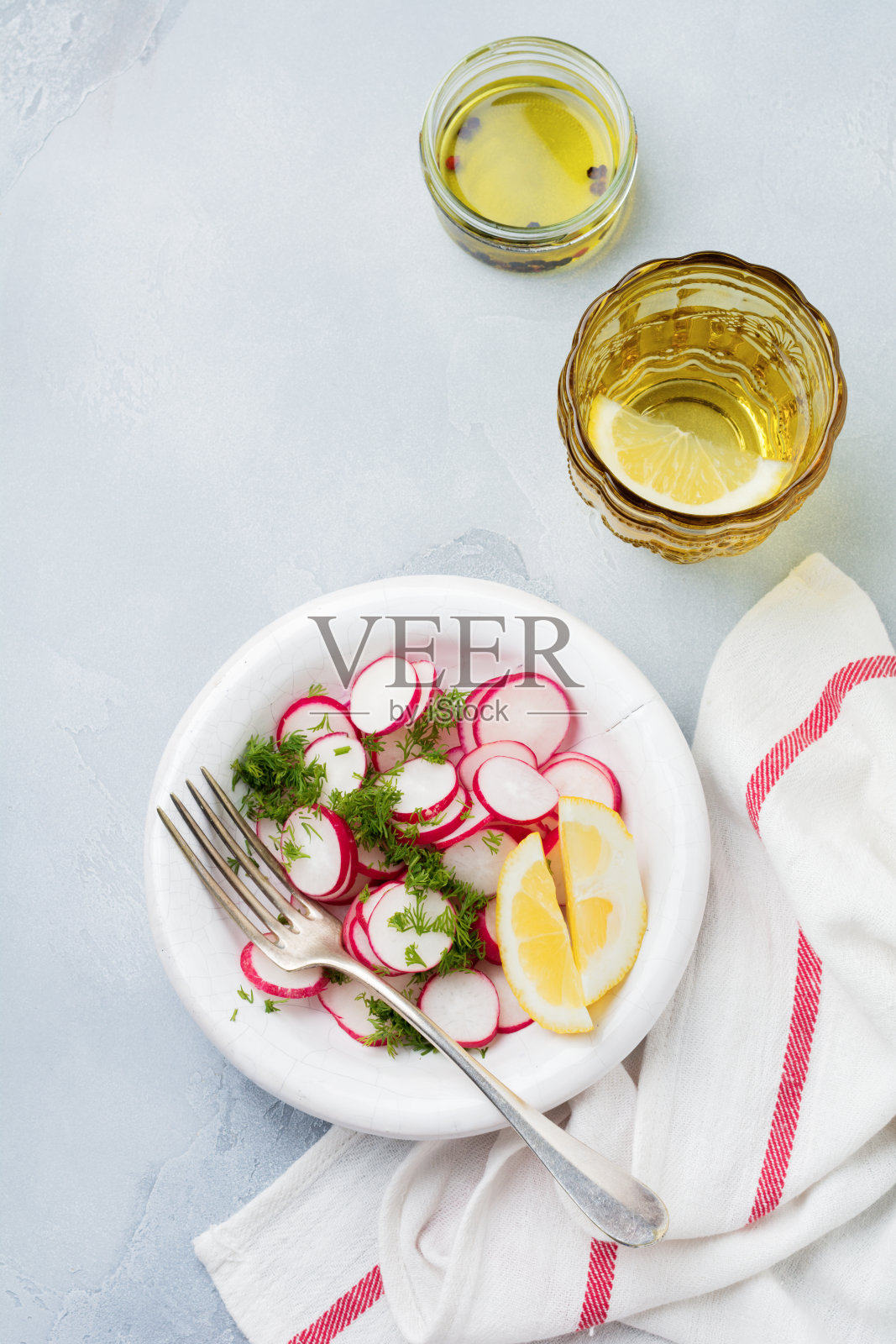 简单的沙拉，新鲜的萝卜与莳萝，柠檬汁和橄榄油在白色陶瓷碗，浅灰色混凝土或石头背景。有选择性的重点。前视图。照片摄影图片