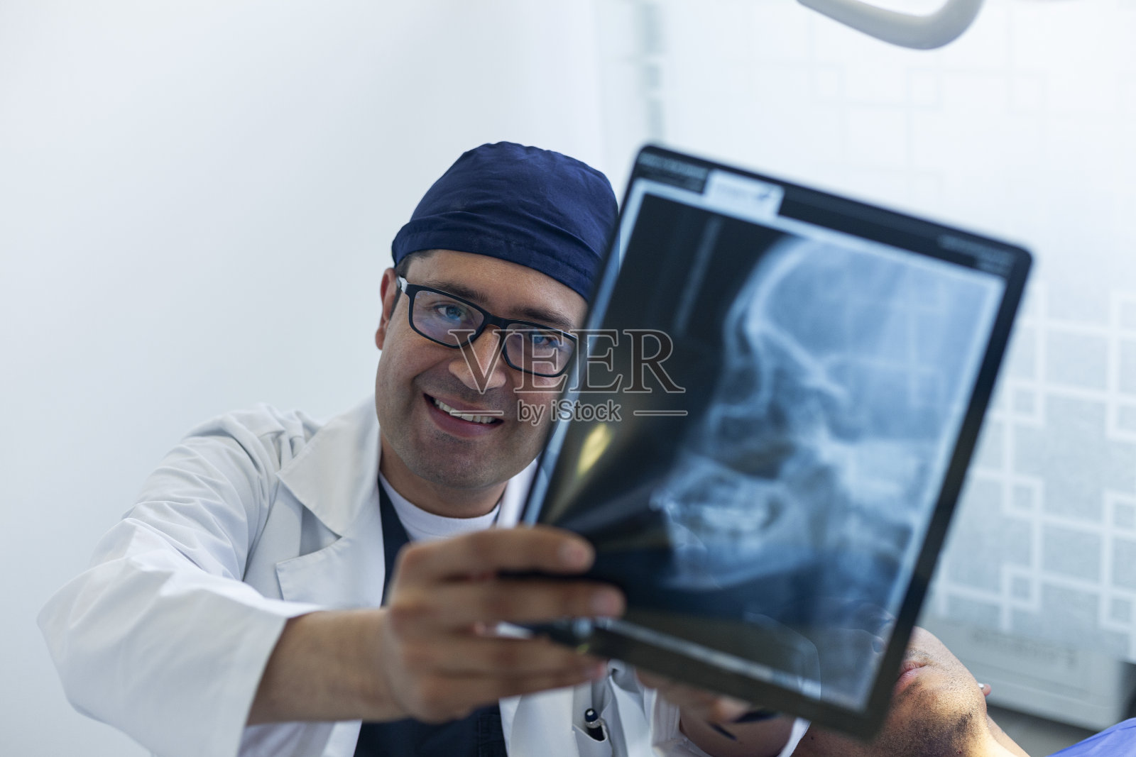 牙医向他的男病人解释要用x光片进行的治疗照片摄影图片